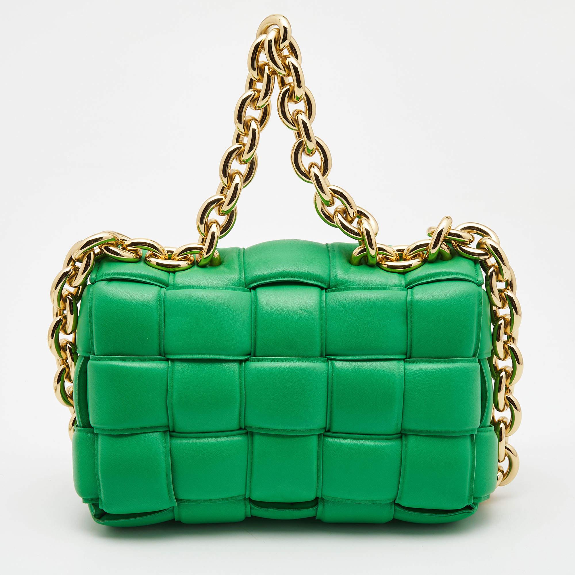 The Bottega Veneta Cassette shoulder bag is a luxurious accessory featuring exquisite padded green leather. It boasts a chic, rectangular silhouette with a chunky chain strap, adding a touch of edgy elegance. This bag is both stylish and functional,