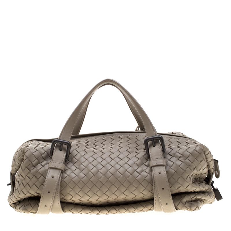 This popular Montaigne bag from the house of Bottega Veneta is elegant. The lovely satchel is woven from grey leather in the brand's signature Intrecciato pattern. It features two handles, a top zipper closure, and black-tone keys and a lock.