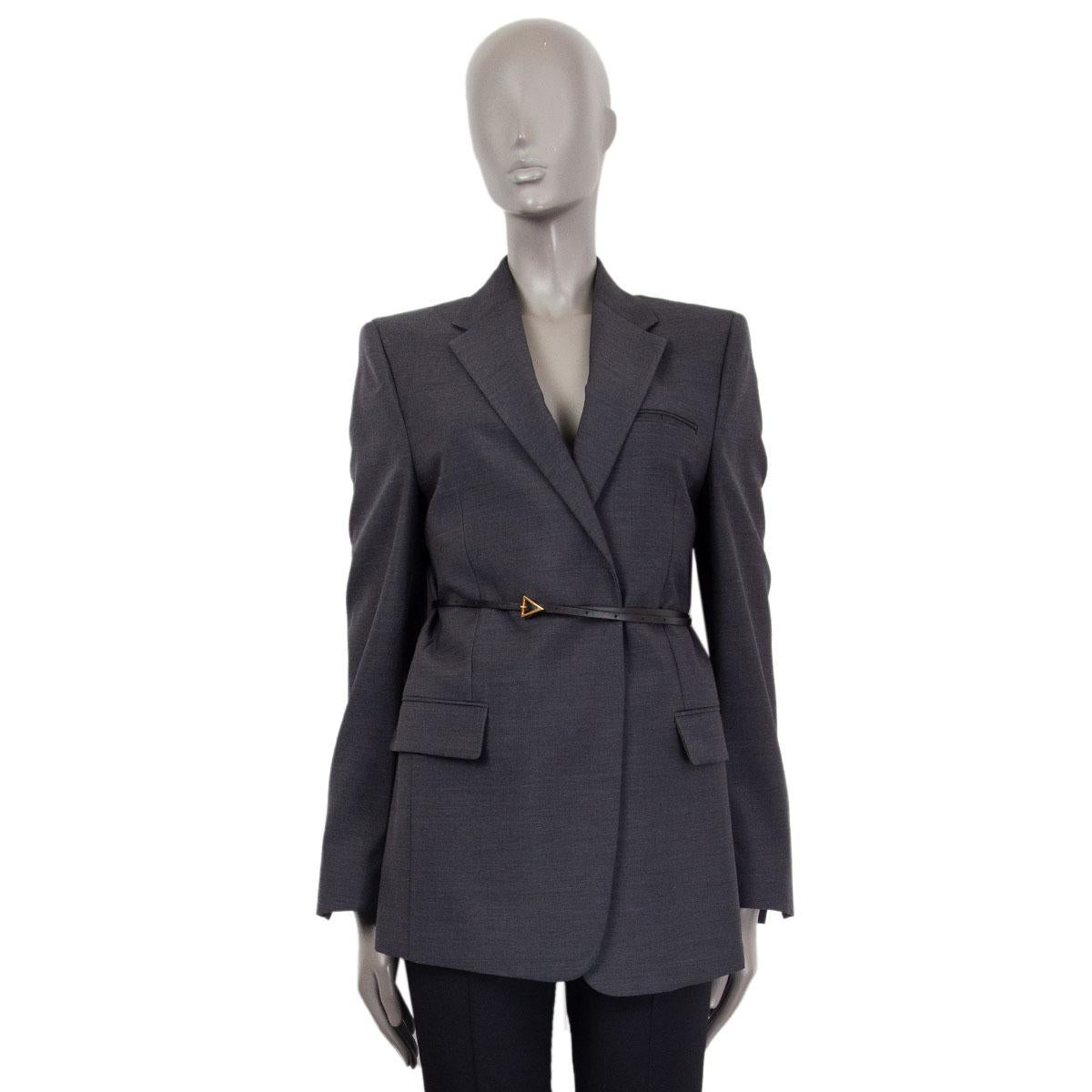 Bottega Veneta belted wool blazer in dark grey wool (100%) with one chest pocket and two front flap pockets. Closes on the front with a leather belt with a gold tone triangular buckle. Lined in silk (100%). Has been worn and is in excellent