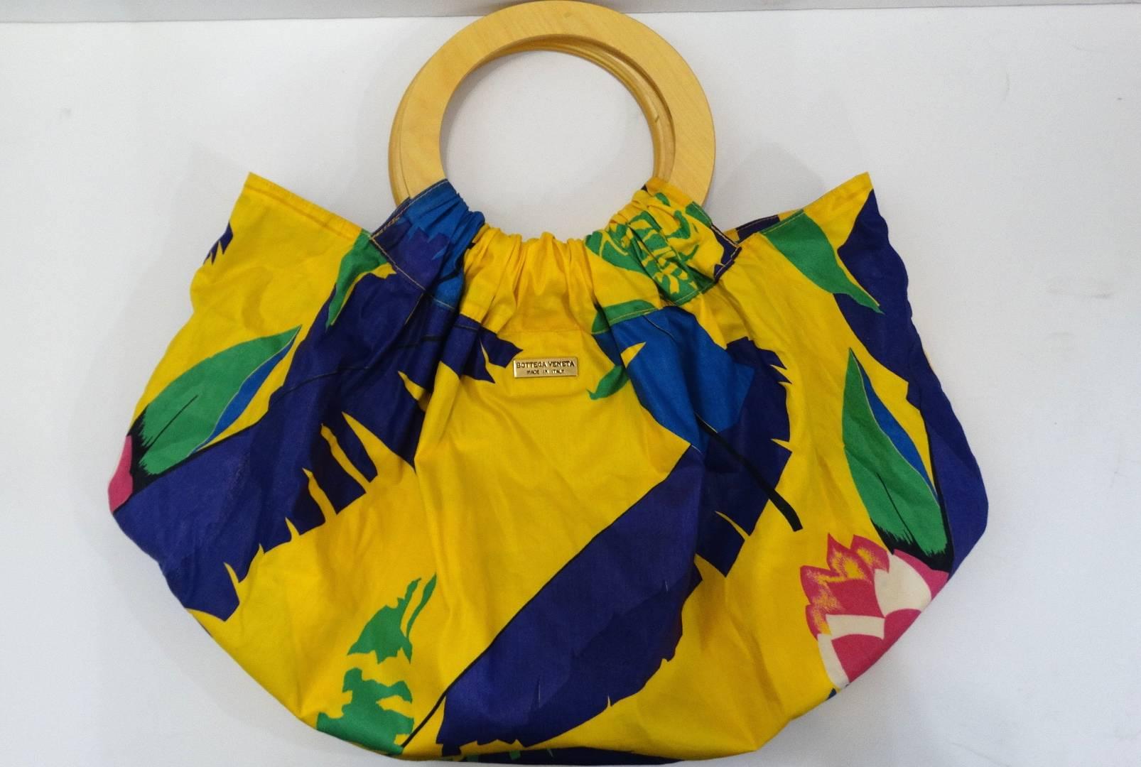 Your perfect summer bag has arrived! The most adorable Hawaiian floral printed bag from iconic label Bottega Veneta! Made of a cotton based fabric and printed with a bold yellow, blue, pink and green Hawaiian inspired floral pattern! Fabric gathers