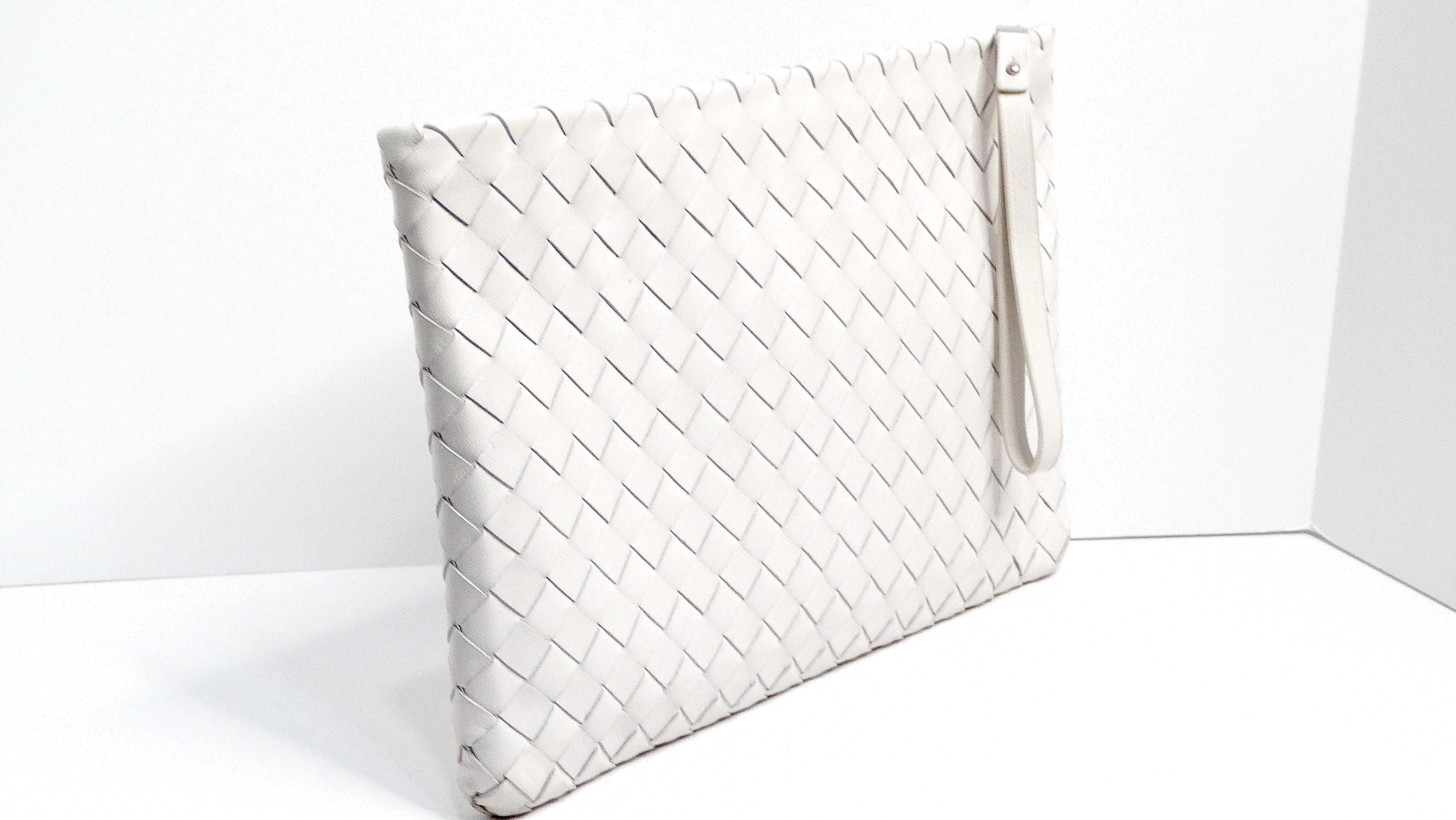 The Bottega Veneta Intrecciato Agate Leather Wrist Pouch is a refined and versatile accessory, crafted from light grey leather with the brand's signature small square weft design. Made in Italy, this pouch exudes sophistication with its silver-tone