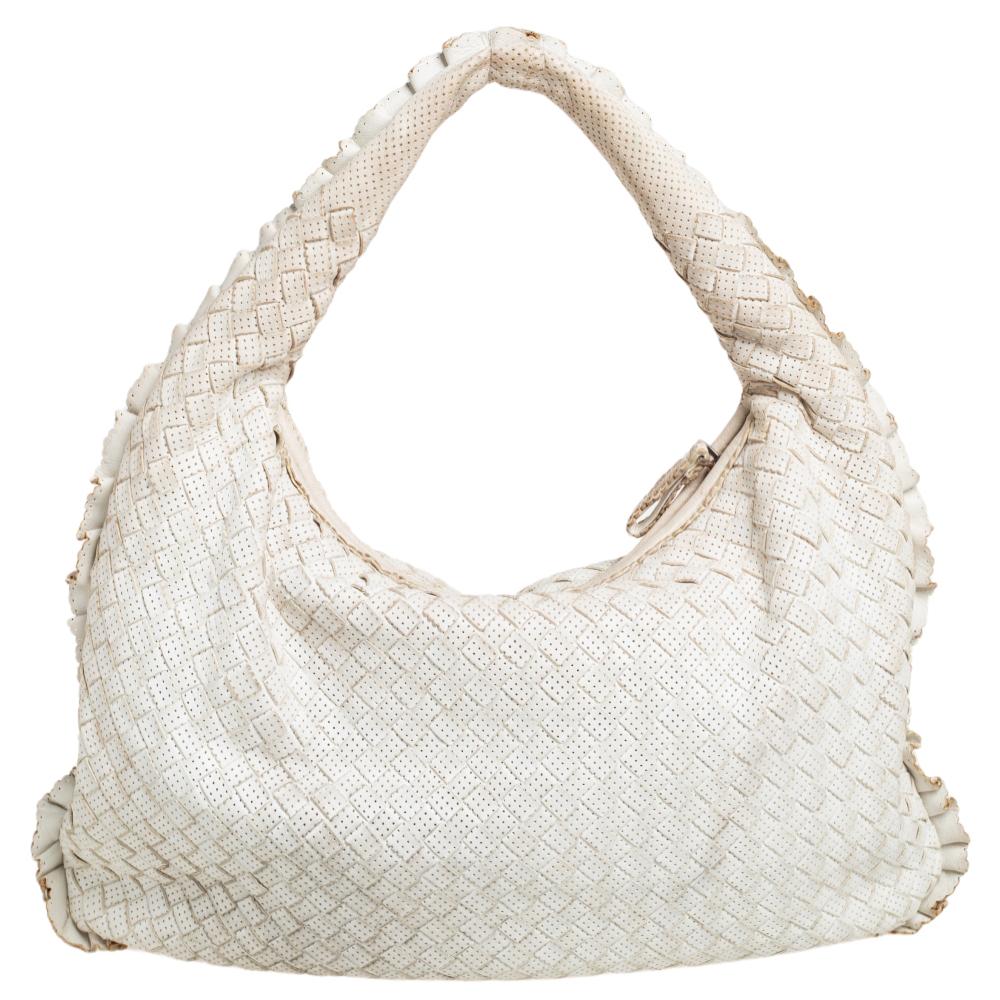 The excellent craftsmanship of this Bottega Veneta handbag ensures a brilliant finish and a rich appeal. Woven from perforated leather in their signature Intrecciato pattern, the hobo bag is provided with minimal gold-tone hardware. It features a