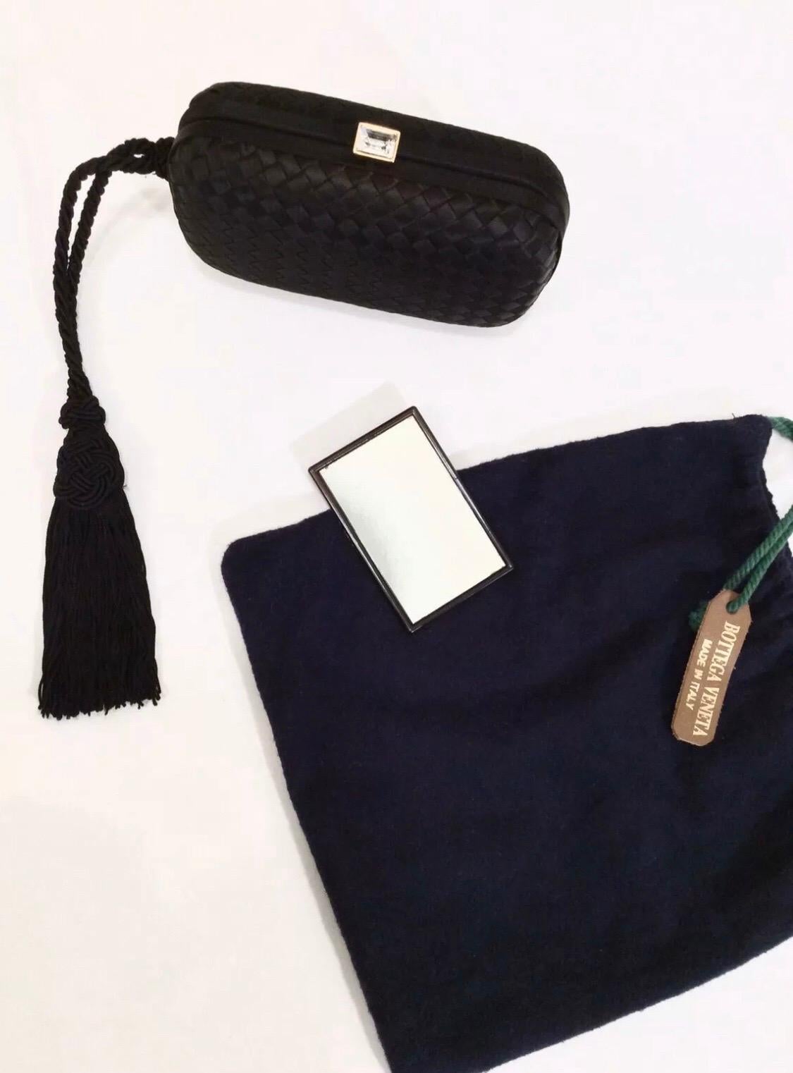 Elevate your evening look with this Bottega clutch! Circa 1980s, this clutch is crafted from black silk and features Bottega's signature woven pattern. Clutch includes a free hanging side tassel and a gold plated press lock closure with a center