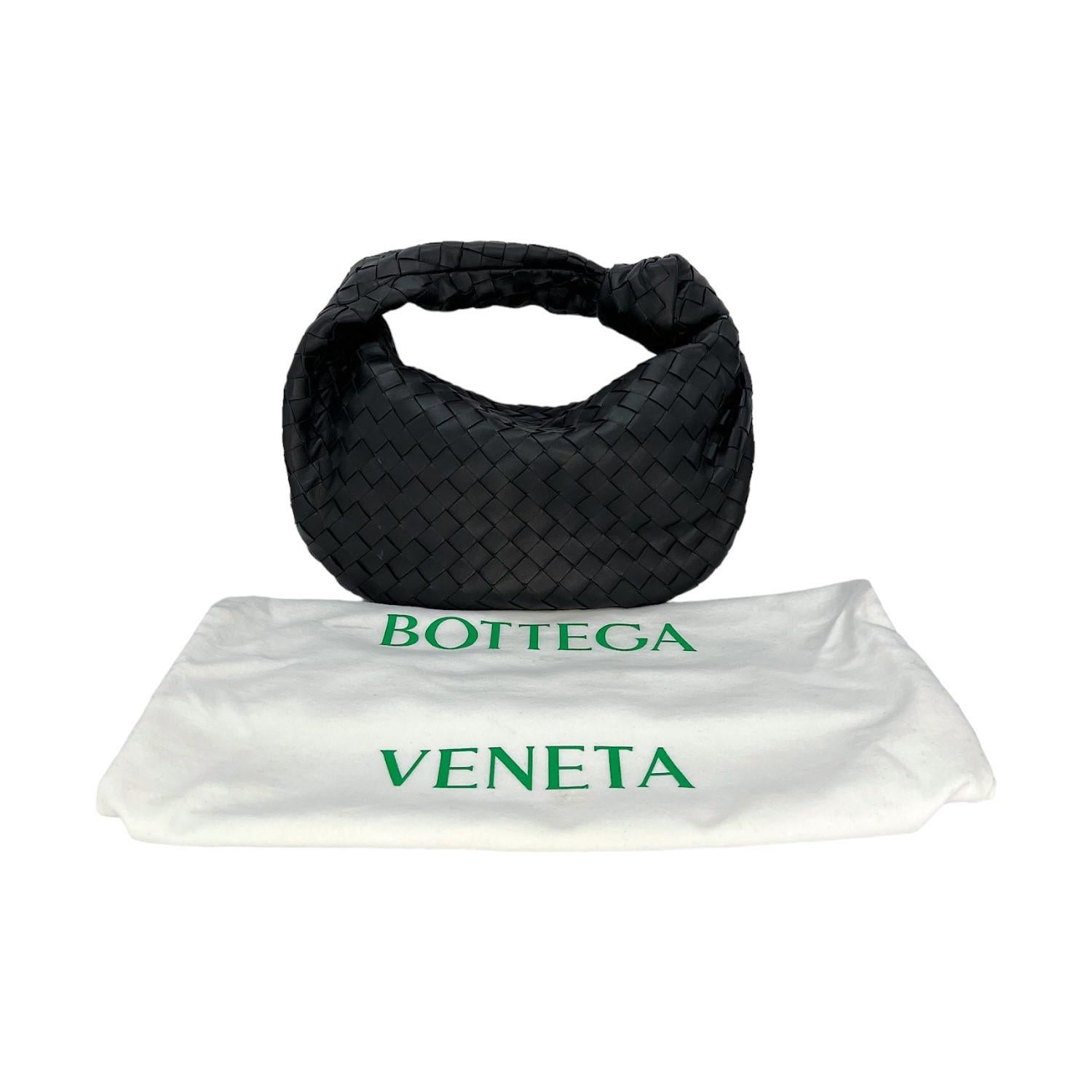 This Bottega Veneta Intrecciato Teen Jodie was made in Italy and it is finely crafted of a woven black leather exterior with silver-tone hardware features. It has a woven black leather top handle. It has a zipper closure that opens up to a spacious