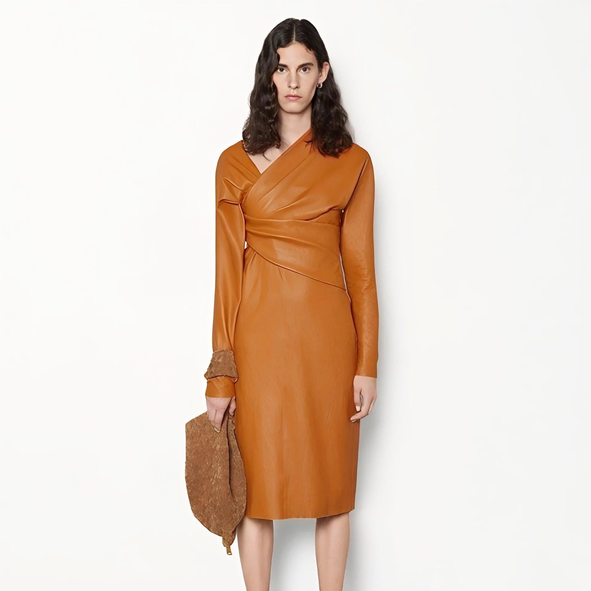 Dalla collezione Pre-Spring 2020, questo abito midi in pelle d'agnello arancione di Bottega Veneta è caratterizzato da ruche sul petto, maniche lunghe e una sapiente lavorazione della pelle.  
 Misure: Maniche (dalla