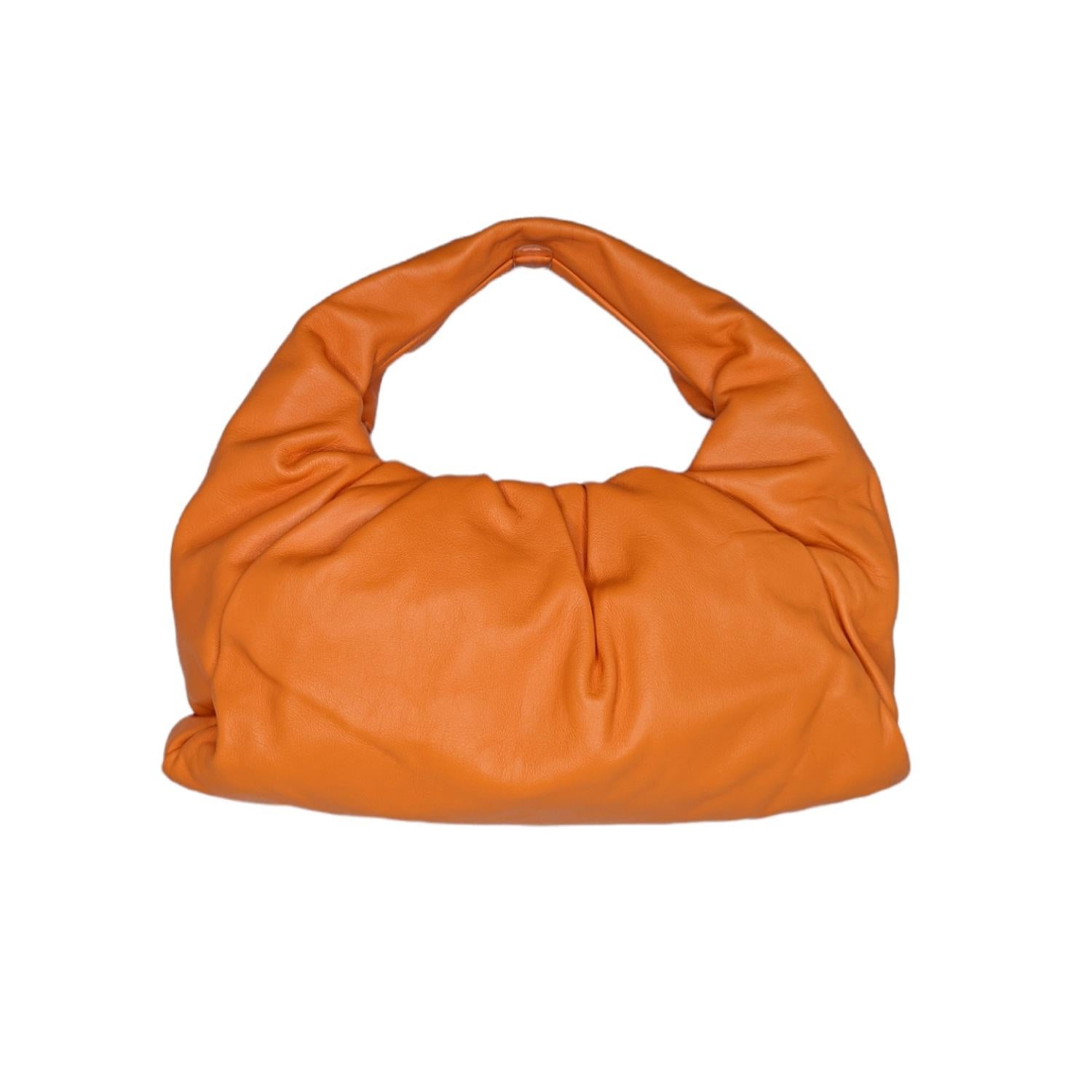Cette pochette élégante est réalisée en cuir de veau de couleur orange clair. Le sac est doté d'un couvercle magnétique en cuir froncé qui s'ouvre sur un intérieur en cuir assorti et une anse supérieure en boucle. Appréciez la sophistication chic de