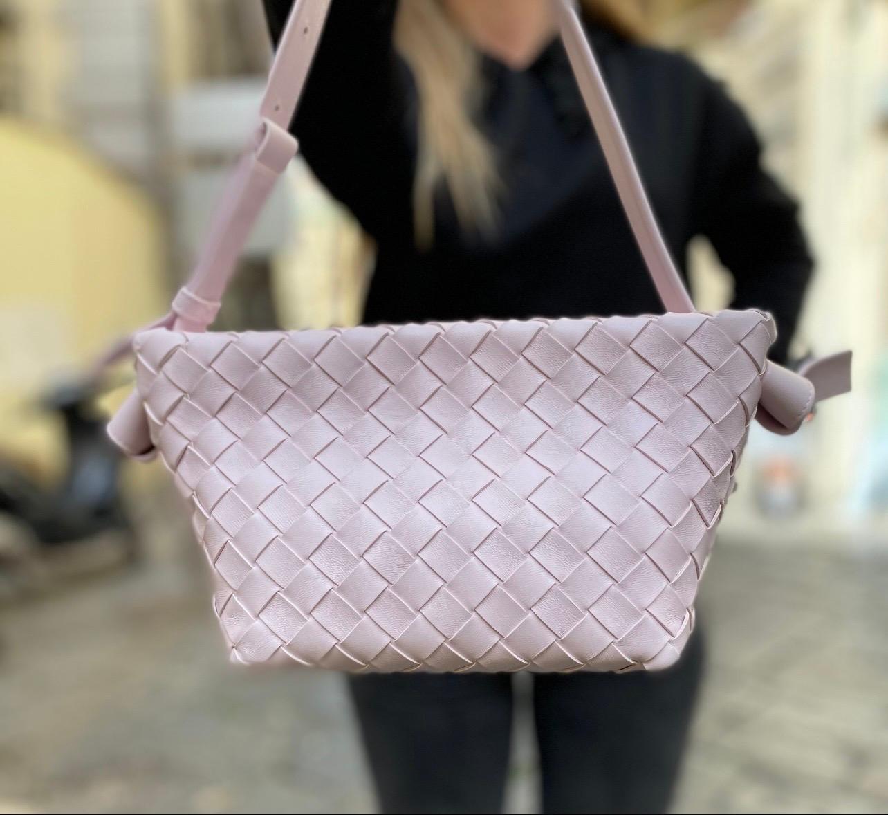 Borsa firmata Bottega Veneta, modello Tie, realizzata in pelle di agnello intrecciata con finiture dorate. Dotata di chiusura magnetica, foderata internamente in pelle, capiente per l'essenziale. Dotata di un manico in pelle liscia regolabile.