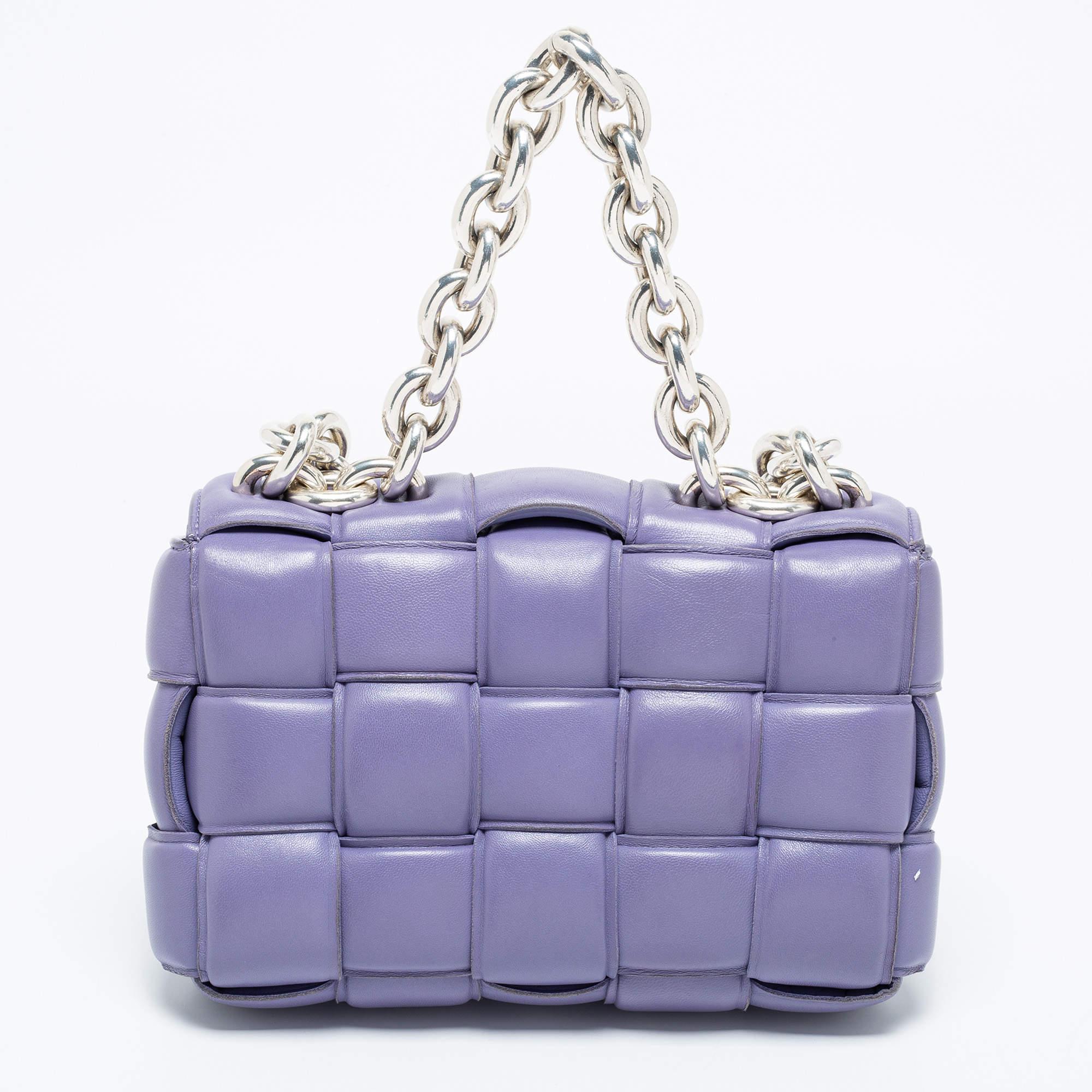 The lovely bag on many fashionistas' minds is the iconic Cassette bag from the house of Bottega Veneta. We have here one in lilac leather, flaunting a padded weave and chunky, metallic chain handles. The insides are well-sized to fit your phone,