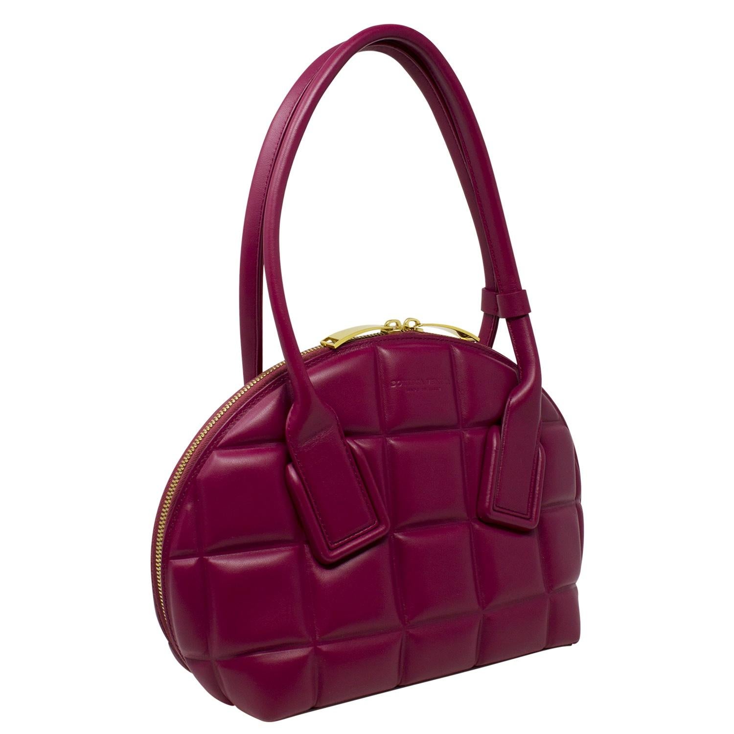 Rare and special Bottega Veneta top handle bag crafted in a beautiful maroon leather with dual rolled handles and a single adjustable shoulder strap. With gold-tone hardware, the zipper opens up to a tonal leather interior with the single interior