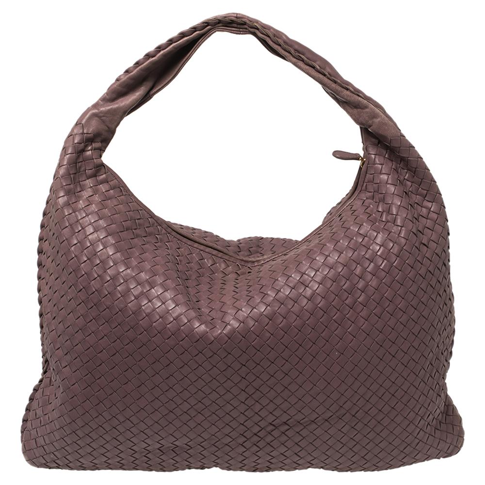 The excellent craftsmanship of this Bottega Veneta hobo ensures a brilliant finish and a rich appeal. Woven from leather in their signature Intrecciato pattern, the mauve-hued bag is provided with minimal gold-tone hardware. It features a loop