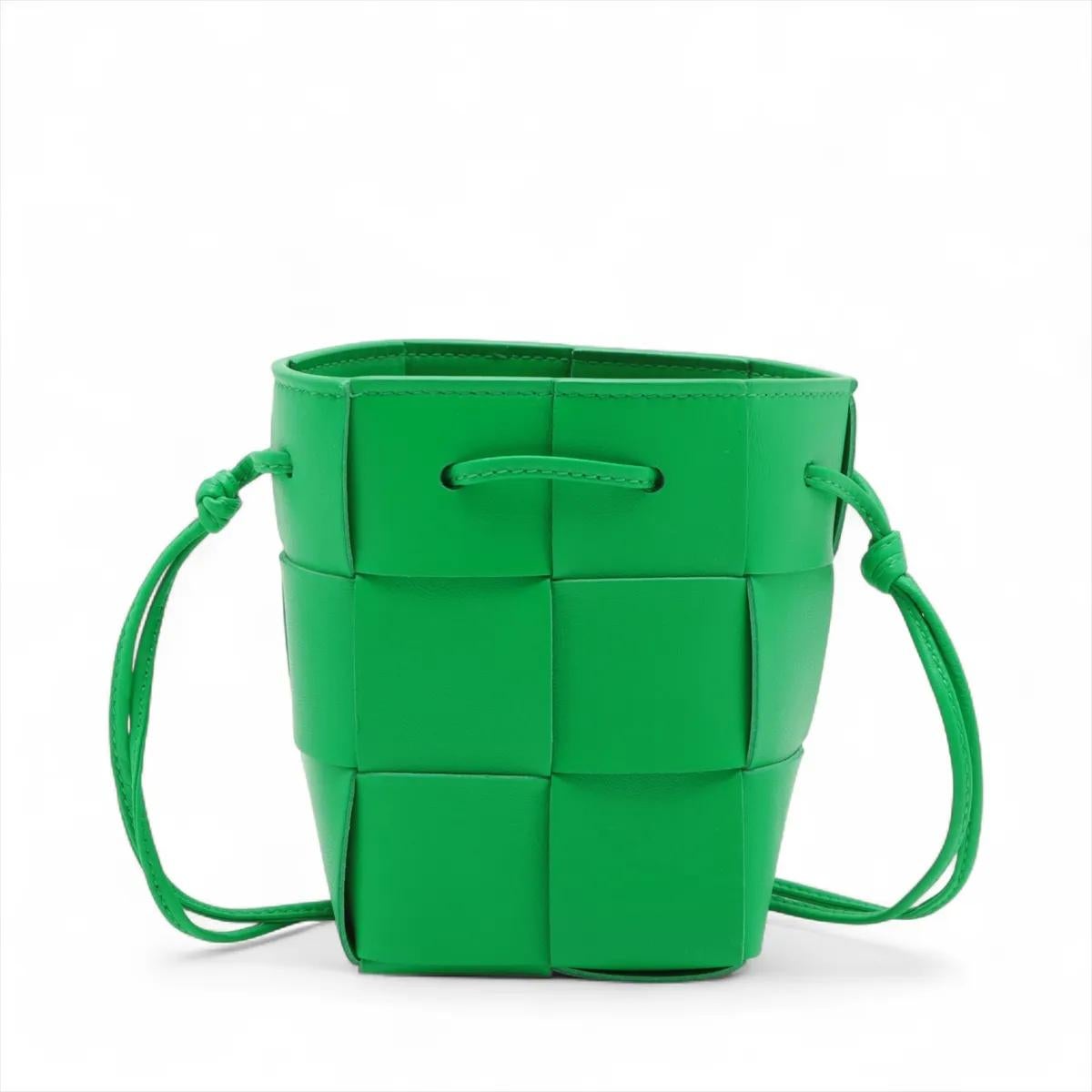 La Bottega Veneta Maxi Intrecciato Cassette Mini Bucket Crossbody Bag in verde è un pezzo forte e compatto che riflette l'iconica maestria del marchio e la sua modernità. Realizzata in morbida pelle con l'inconfondibile trama Intrecciato, la mini