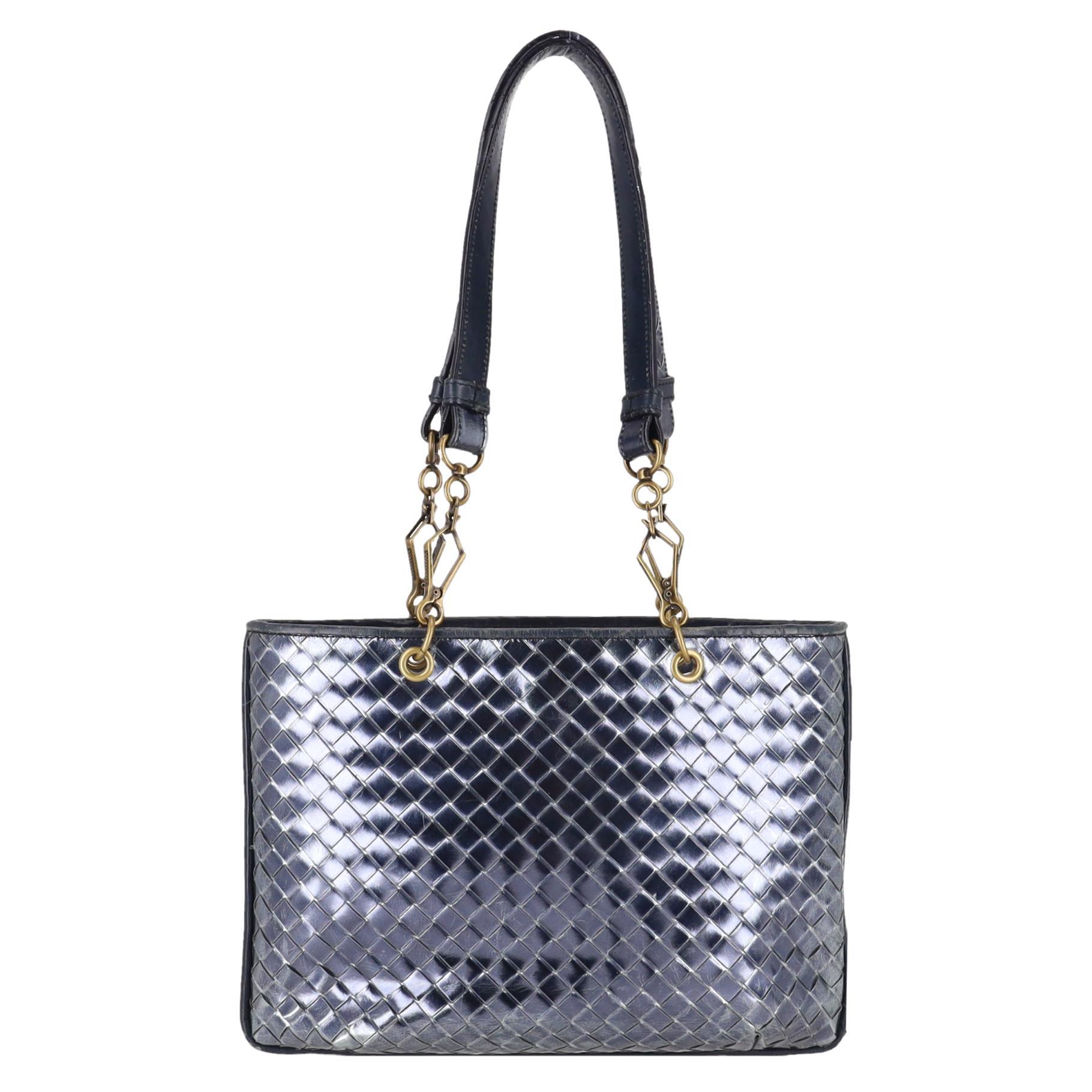 Bottega Veneta Metallic Intrecciato Leather Tote Bag

Dark grey tote bag crafted from metallic leather with purple undertones, designed with the brand's signature Intrecciato weave pattern.

Featuring aged gold hardware and detachable dual top