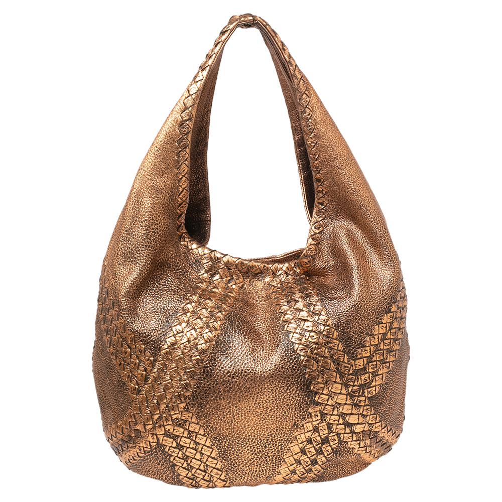 This gorgeous Cervo hobo from the House of Bottega Veneta is made to grant you complete practicality and luxury! Made from metallic rose-gold leather, this hobo flaunts a single sturdy handle and brass-tone fittings. The zipper leads us to a roomy