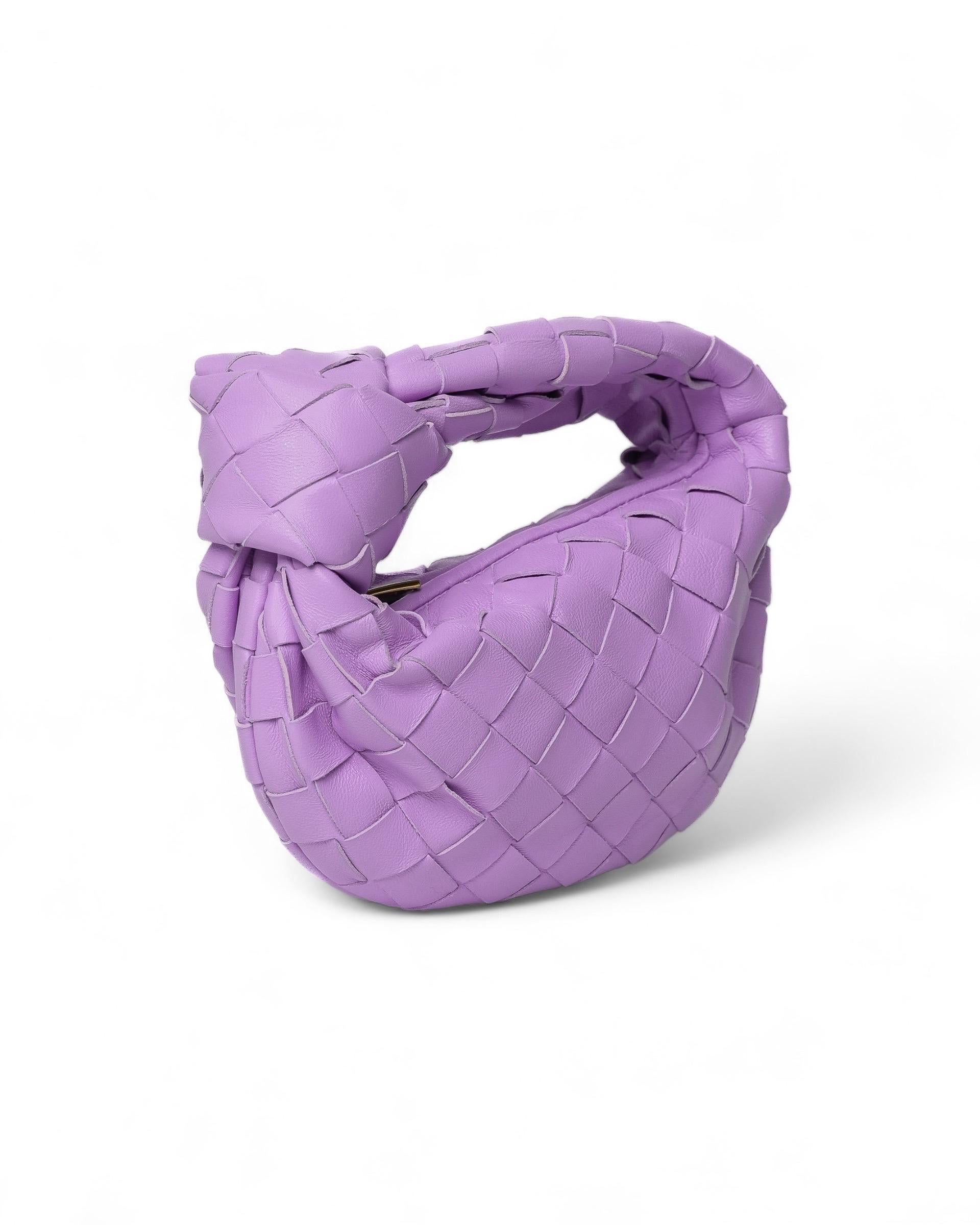Borsa firmata Bottega Veneta, modello Candy JODI, misura Mini, realizzata in pelle di agnello intrecciata color lilla con hardware dorati. Dotata di una chiusura superiore a zip, internamente rivestita in pelle tono su tono, capiente per