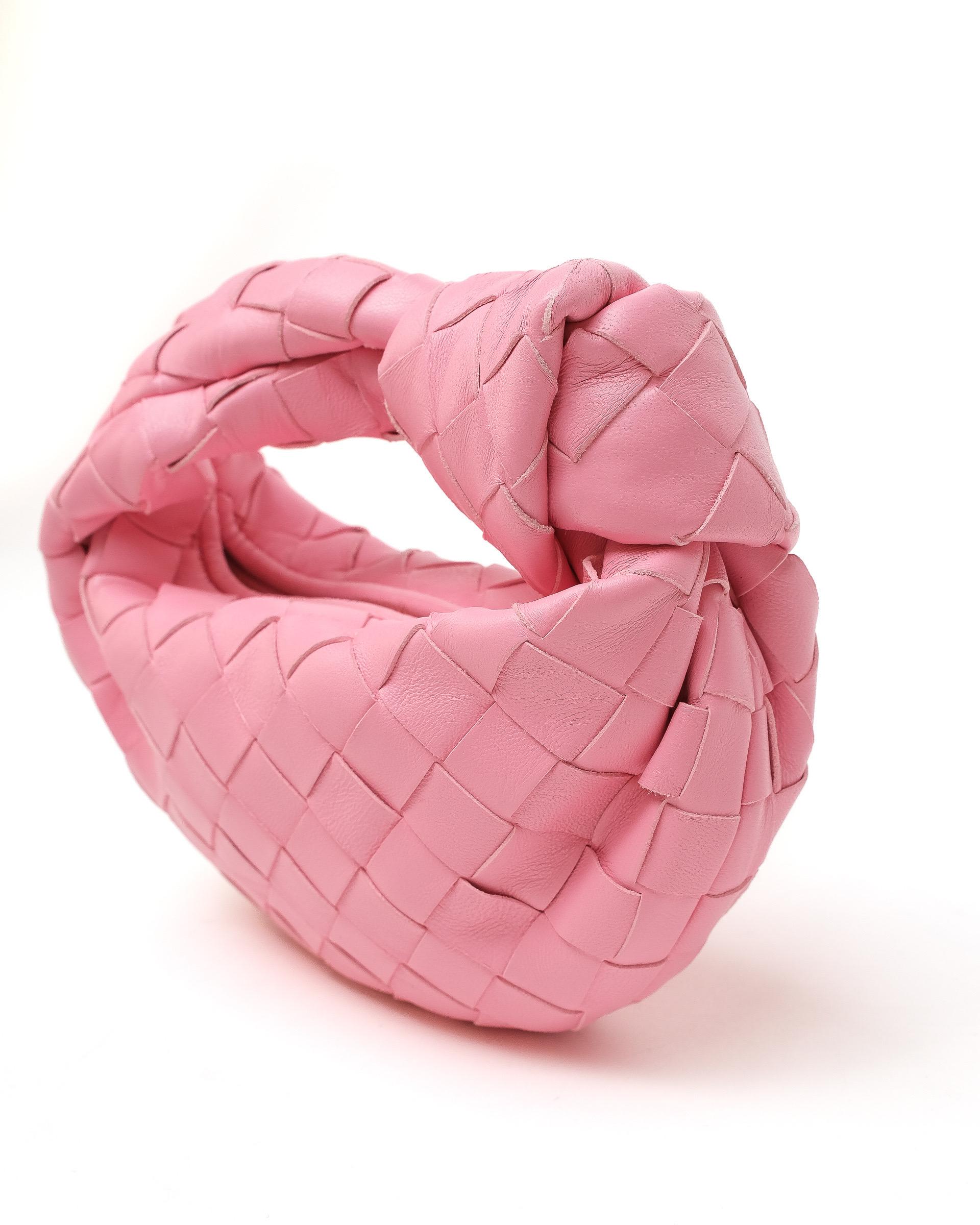 Borsa firmata Bottega Veneta, modello Candy Jodie, misura Mini, realizzata in pelle di agnello intrecciata color rosa con hardware dorati. Dotata di una chiusura superiore a zip, internamente rivestita in pelle tono su tono, capiente per