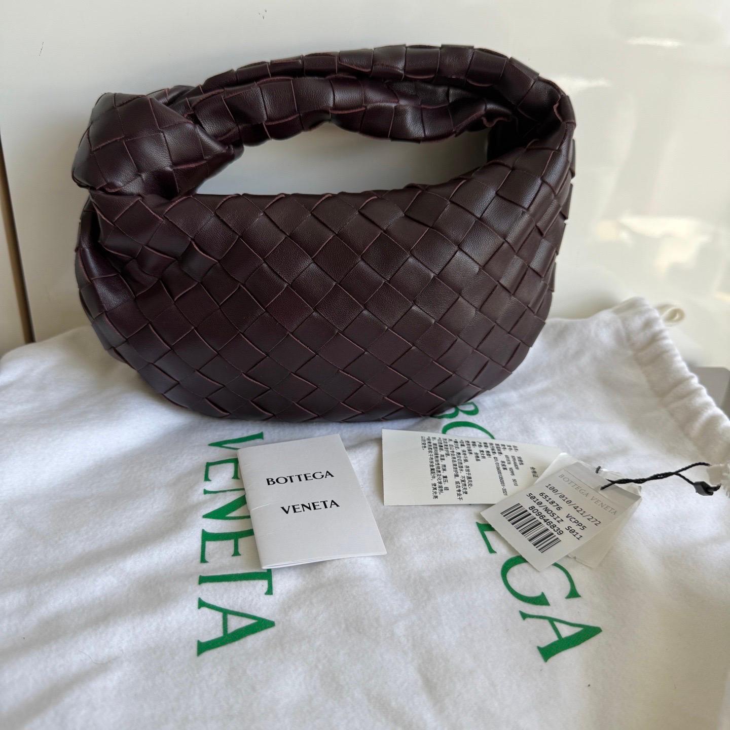 La Bottega Veneta Jodie Mini en elegante piel burdeos ofrece el equilibrio perfecto entre practicidad y lujo. Su tamaño mini lo convierte en un bolso ideal para el día a día, mientras que el icónico tejido Intrecciato es toda una declaración de