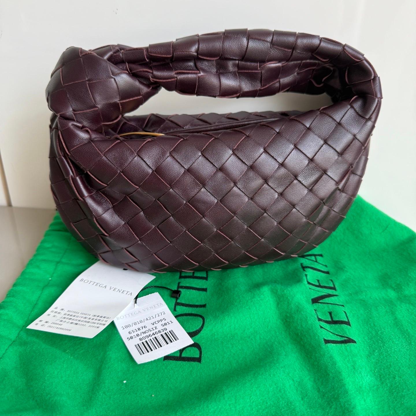 La Bottega Veneta Jodie Mini en elegante piel burdeos ofrece el equilibrio perfecto entre practicidad y lujo. Su tamaño mini lo convierte en un bolso ideal para el día a día, mientras que el icónico tejido Intrecciato es toda una declaración de