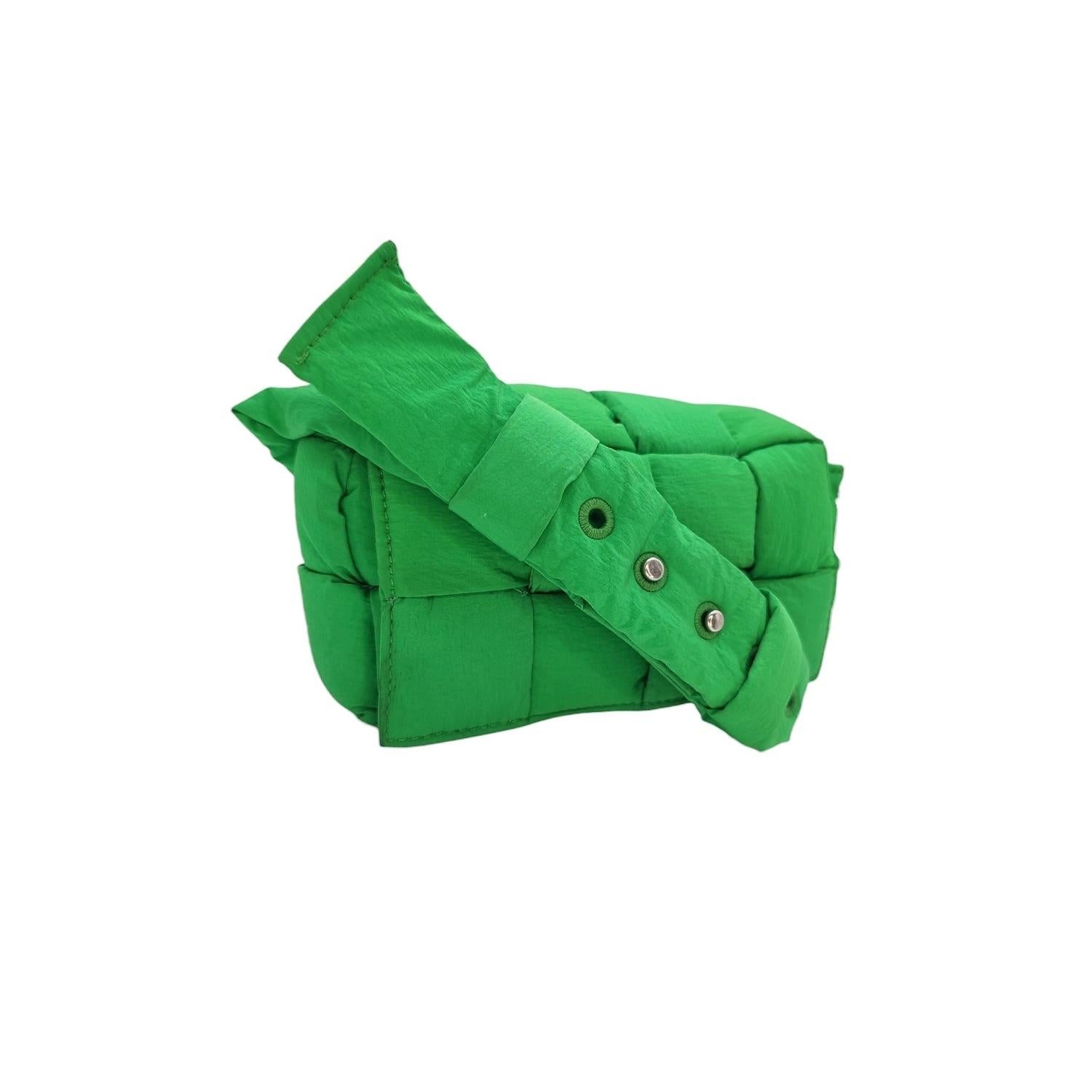 Indulge in luxury with our exquisite Bottega Veneta Nylon Cassette Mini Belt Bag. Crafted of woven nylon exterior with a matching parakeet (green) nylon strap and silver-tone hardware. The magnetic closure opens to a spacious interior with a hanging