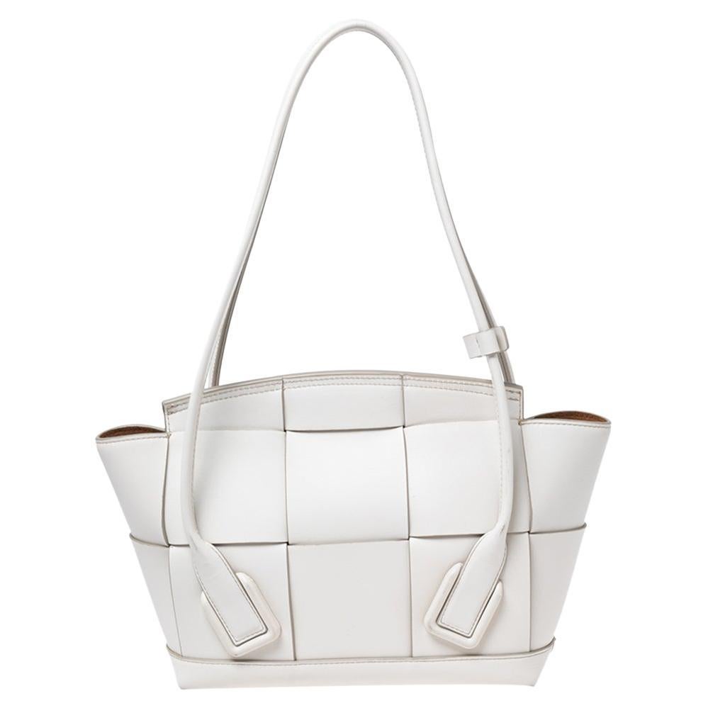 This Arco tote from the House of Bottega Veneta is great for everyday use. It is made from off-white Intrecciato leather on the exterior and showcases dual handles, a sturdy shape, and silver-toned hardware. It is provided with a spacious