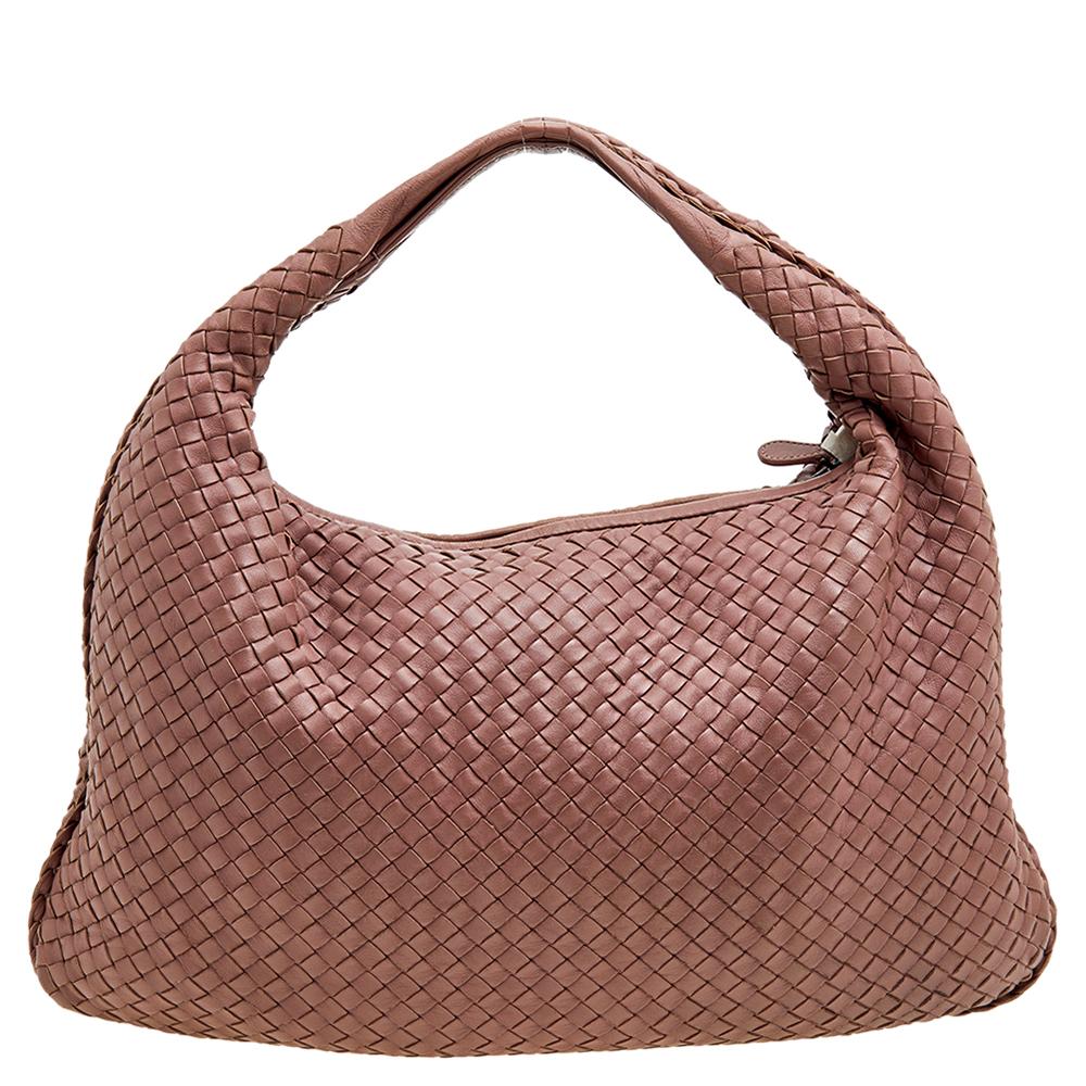 The excellent craftsmanship of this Bottega Veneta hobo ensures a brilliant finish and a rich appeal. Woven from leather in their signature Intrecciato pattern, the old rose-hued bag is provided with minimal hardware. It features a loop handle and a