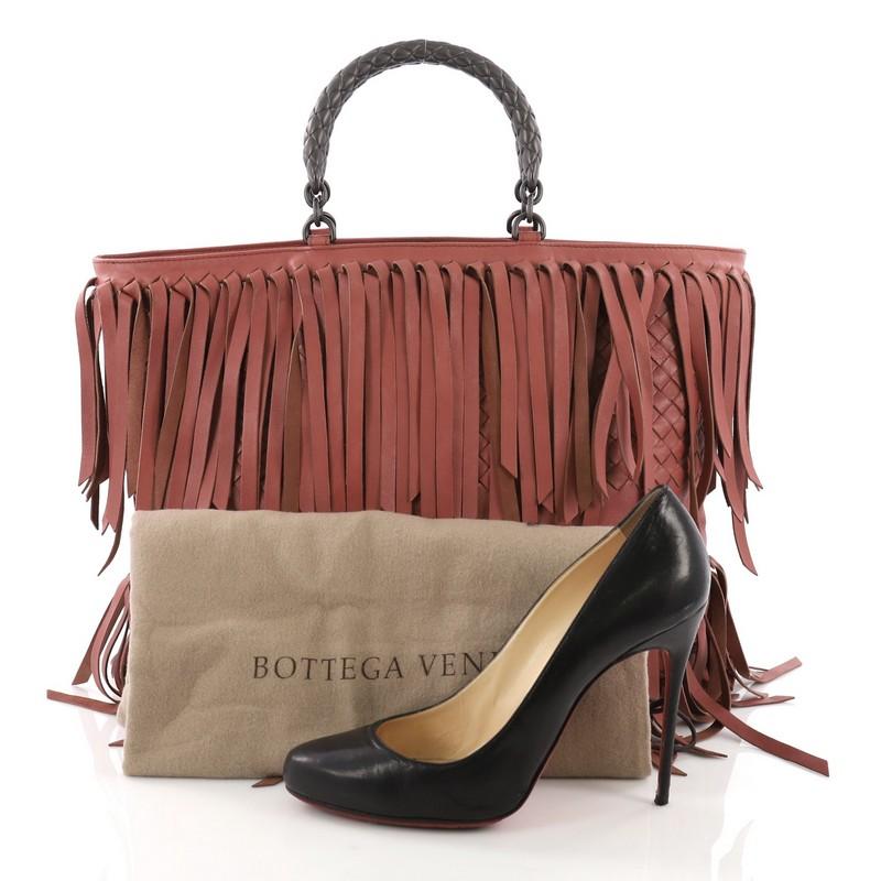 This Bottega Veneta Open Tote Fringe Intrecciato Nappa Large, crafted from pink intrecciato nappa leather, features dual woven top handles, fringe detailing, and matte gunmetal-tone hardware. It opens to a taupe suede interior with zip pocket.