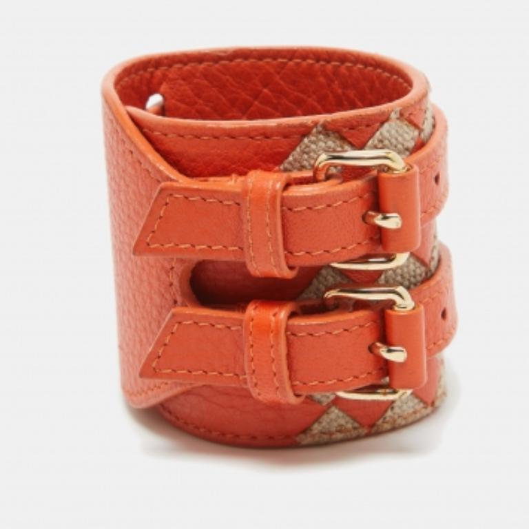 Experimenta la cautivadora fusión del naranja vibrante y el beige suave en esta pulsera Bottega Veneta. Elaborado con meticulosa atención, su cuero y yute entretejidos combinan a la perfección. El diseño de doble hebilla emana un encanto refinado,