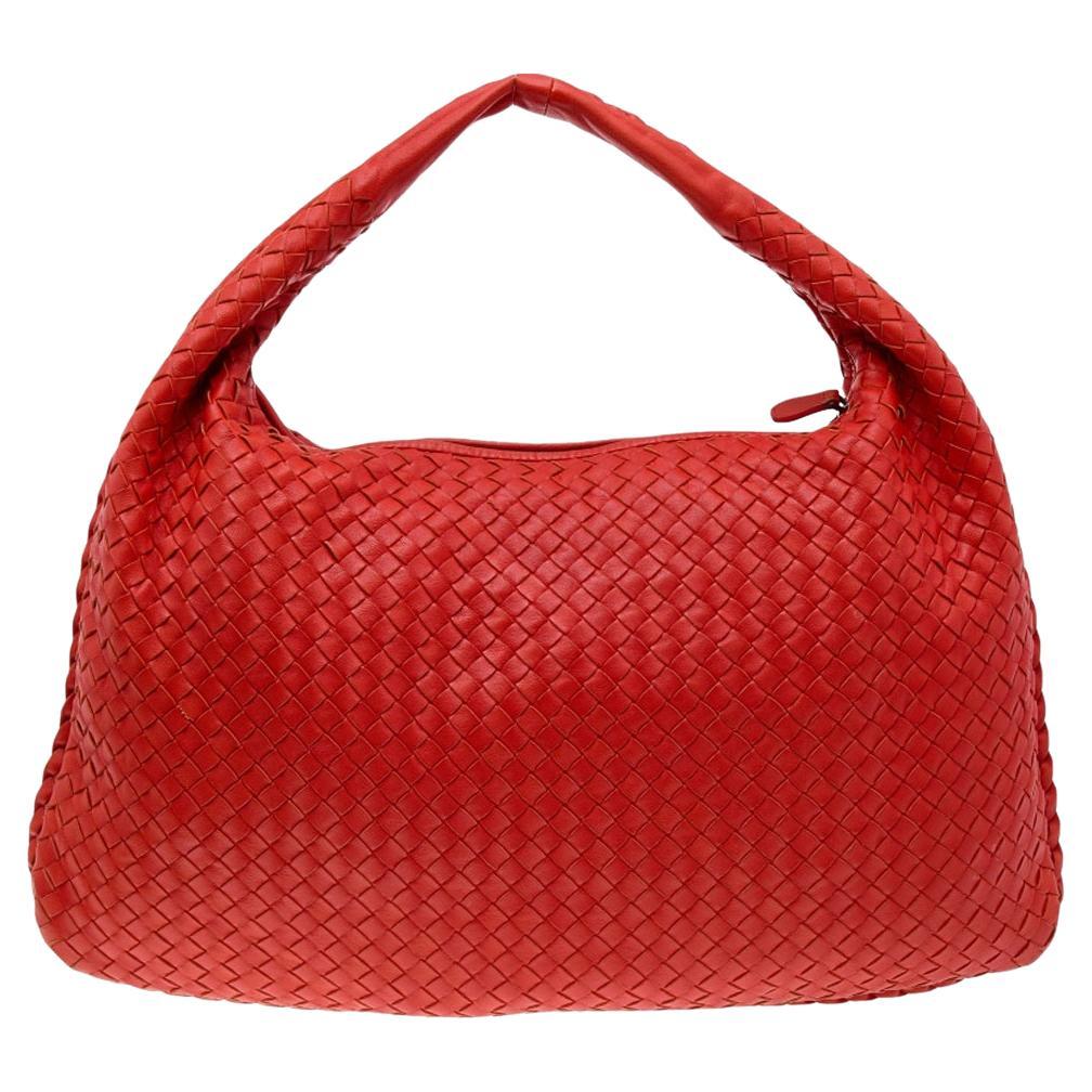 The excellent craftsmanship of this Bottega Veneta hobo ensures a brilliant finish and a rich appeal. Woven from leather in their signature Intrecciato pattern, the crimson orange-hued bag is provided with minimal hardware. It features a loop handle