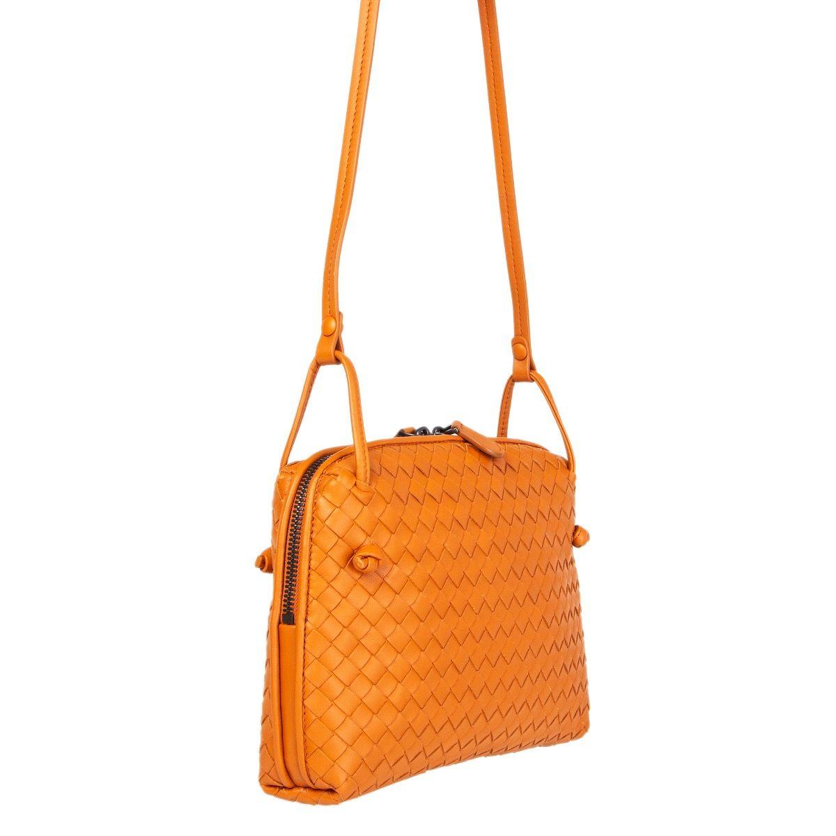 Bottega Veneta 'Nodini' cross-body in orange woven nappa leather. Opens with a two-way zipper on top. Lined in dark taupe suede with one open pocket against the front and a zipper pocket against the back. Has an adjustable shoulder strap. Comes with