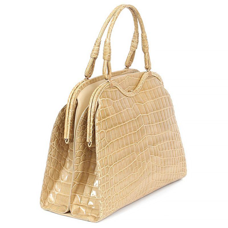 Bottega Veneta handbag in pale dusty yellow shiny crocodile skin. Opens in the middle with a hidden magnet for your paper and magazines. Frame-closure on the left and right. Lined in light blue leather with a zipper pocket against the centre. Has