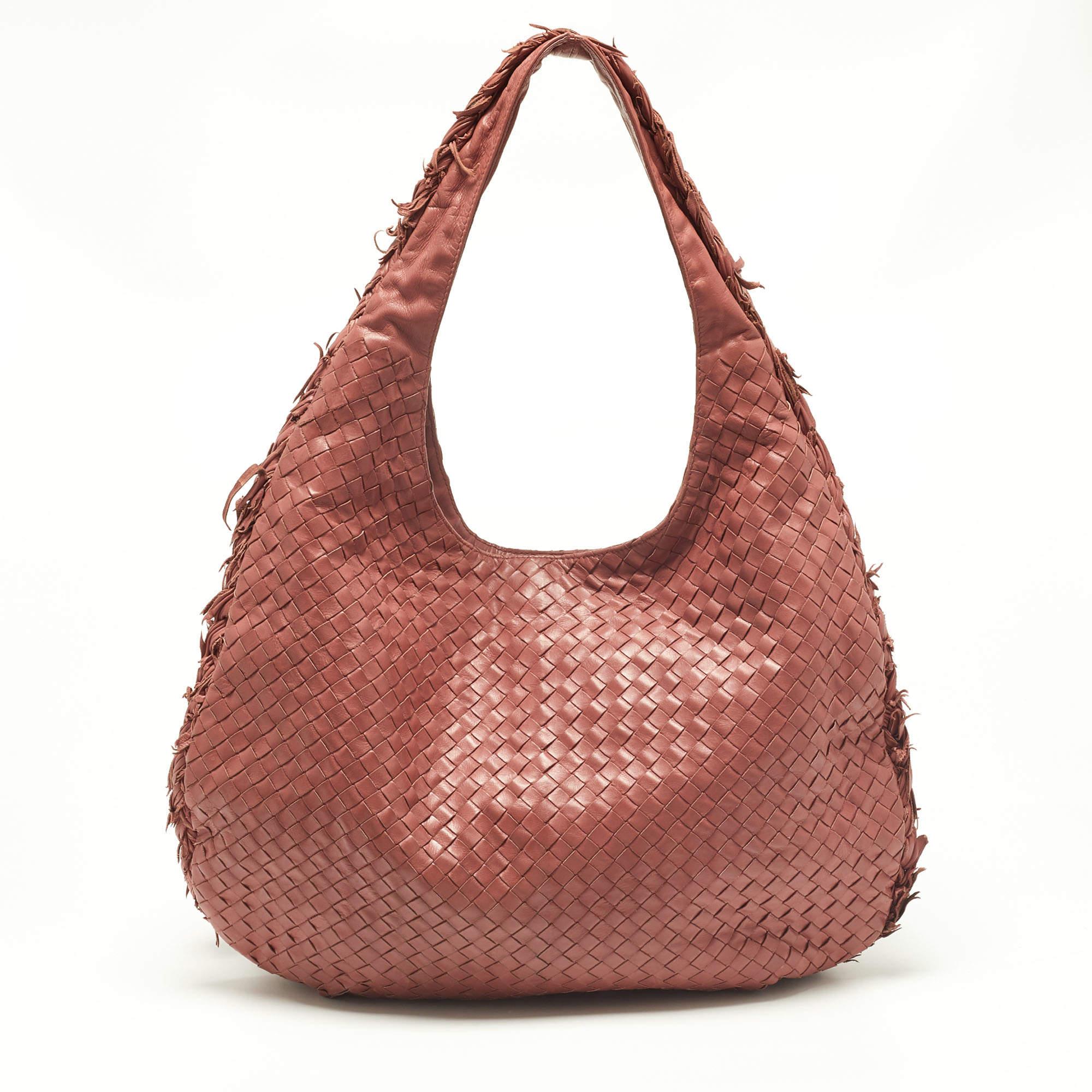 The excellent craftsmanship of this Bottega Veneta hobo ensures a brilliant finish and a rich appeal. Woven from leather in their signature Intrecciato pattern, the peach bag is provided with minimal hardware. It features a single handle and a top