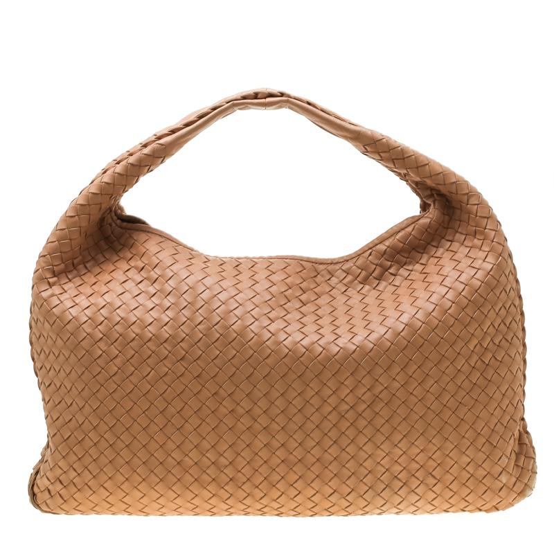 This hobo by Bottega Veneta is durable and practical. Woven from leather in their signature Intrecciato pattern, the peach bag is provided with minimal black-tone hardware. It features a loop handle and a top zip closure which secure a spacious