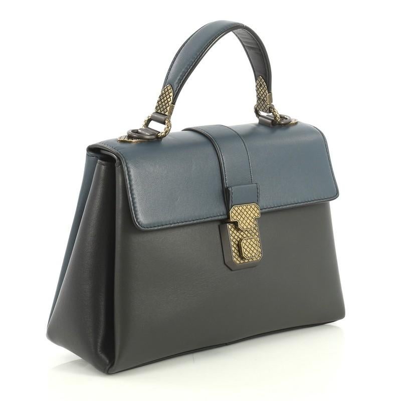 This Bottega Veneta Piazza Top Handle Bag Leather with Intrecciato Detail Small, crafted from black and blue leather, features flap top handle and matte gold and gunmetal-tone hardware. Its flap top with slide-lock closure opens to a neutral suede