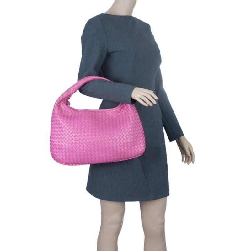 Complete a stunning daytime look with this beautiful Bottega Veneta hobo. Its pink leather exterior is designed with the iconic Intrecciato weave, giving it a luxurious and artisanal look. This hobo has a self-covered handle with leather rings,
