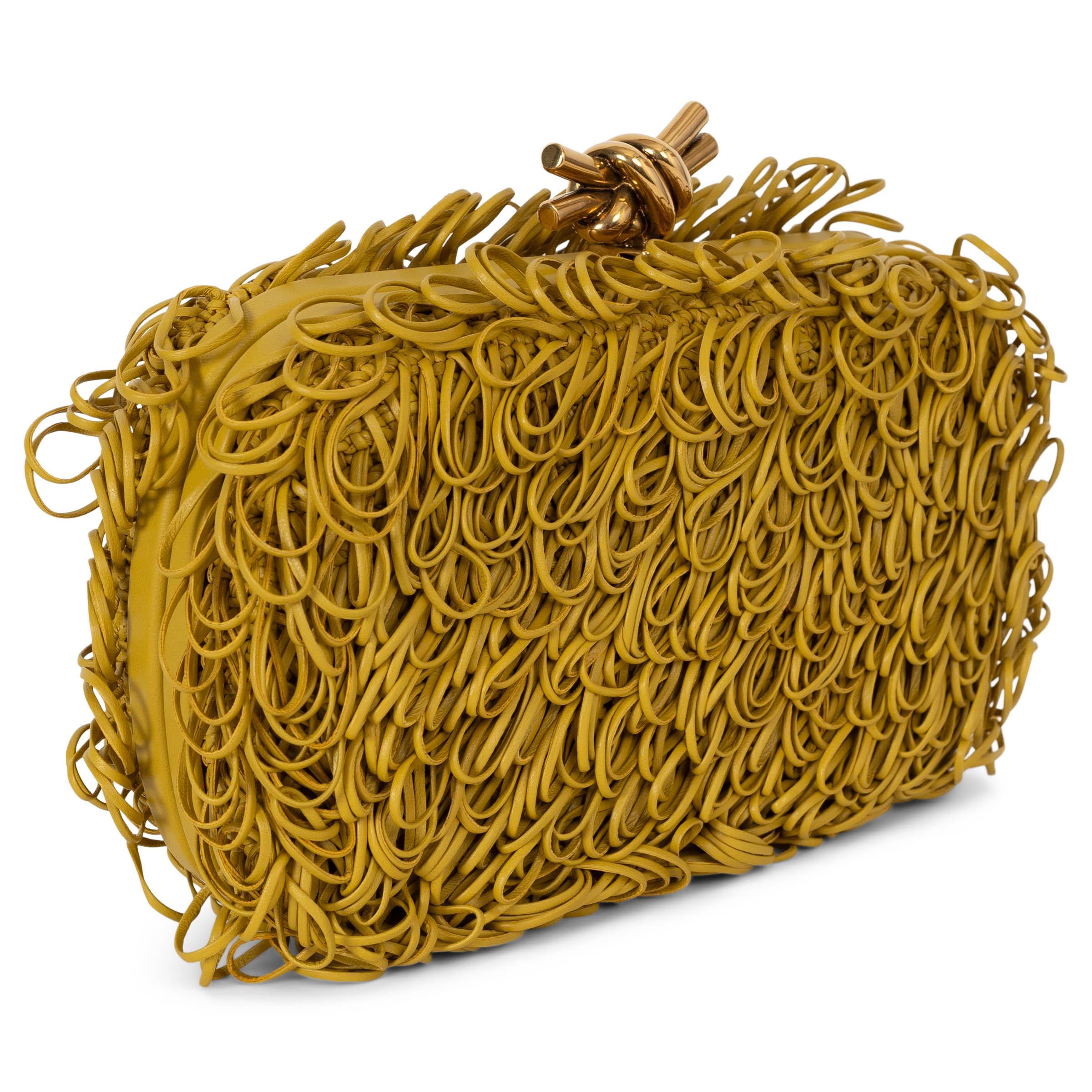 This 100% authentic Bottega Veneta Knot minaudiere clutch in Pollen (yellow) looped leather strings is a true statement of artistry and craftsmanship. A reimagined icon of the house, the intricate design showcases the signature looped leather