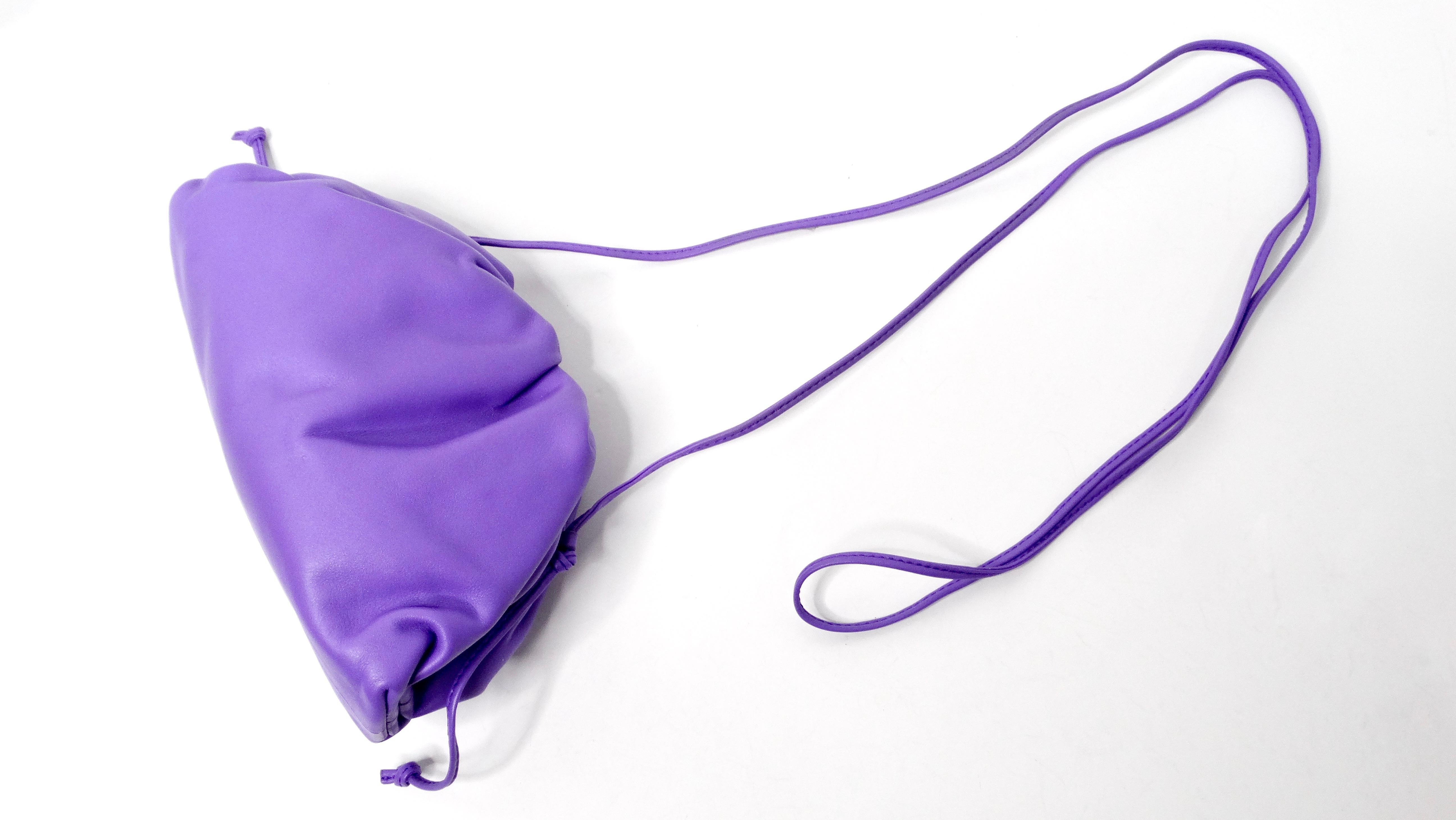 The Bottega Veneta Purple Butter Calfskin Mini Pouch Crossbody Bag is a captivating accessory that epitomizes contemporary luxury and timeless elegance. Crafted from sumptuous calfskin leather in a stunning purple butter hue, this mini pouch