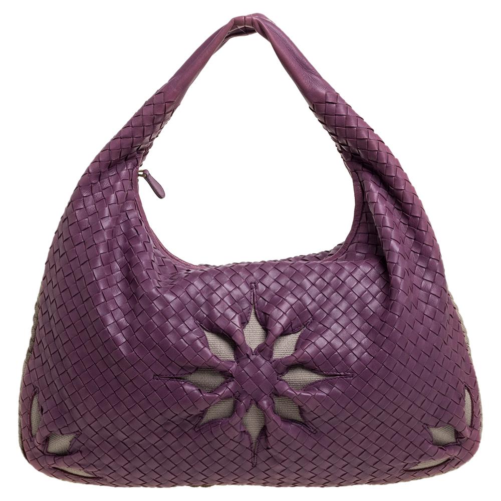 Cute and functional, this hobo from Bottega Veneta is a piece you must own! It is crafted from purple leather in the brand's signature Intrecciato pattern and styled with cut-out floral details and a single top handle. It opens to a suede-lined