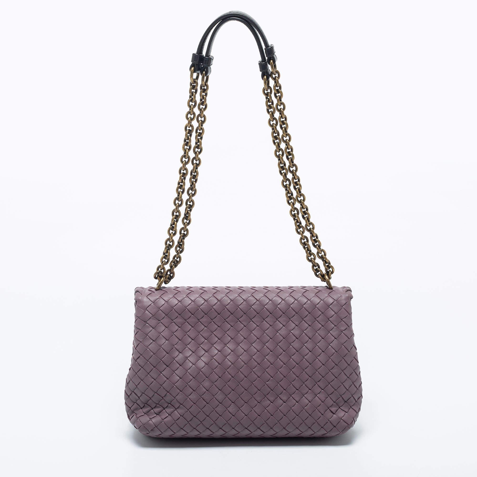Bottega Veneta's Olimpia bag presents the label's artistry in fine craftsmanship and classic designs. Woven in their Intrecciato technique with leather, it features a lovely purple shade, dual shoulder straps, and a front flap that opens to reveal a