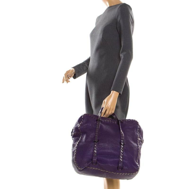 This leather handbag from Bottega Veneta exudes class and charm. Brilliantly designed it is high on functionality and features two handles. The interior is suede lined and houses a zip pocket. Carry this purple bag to your next event for a