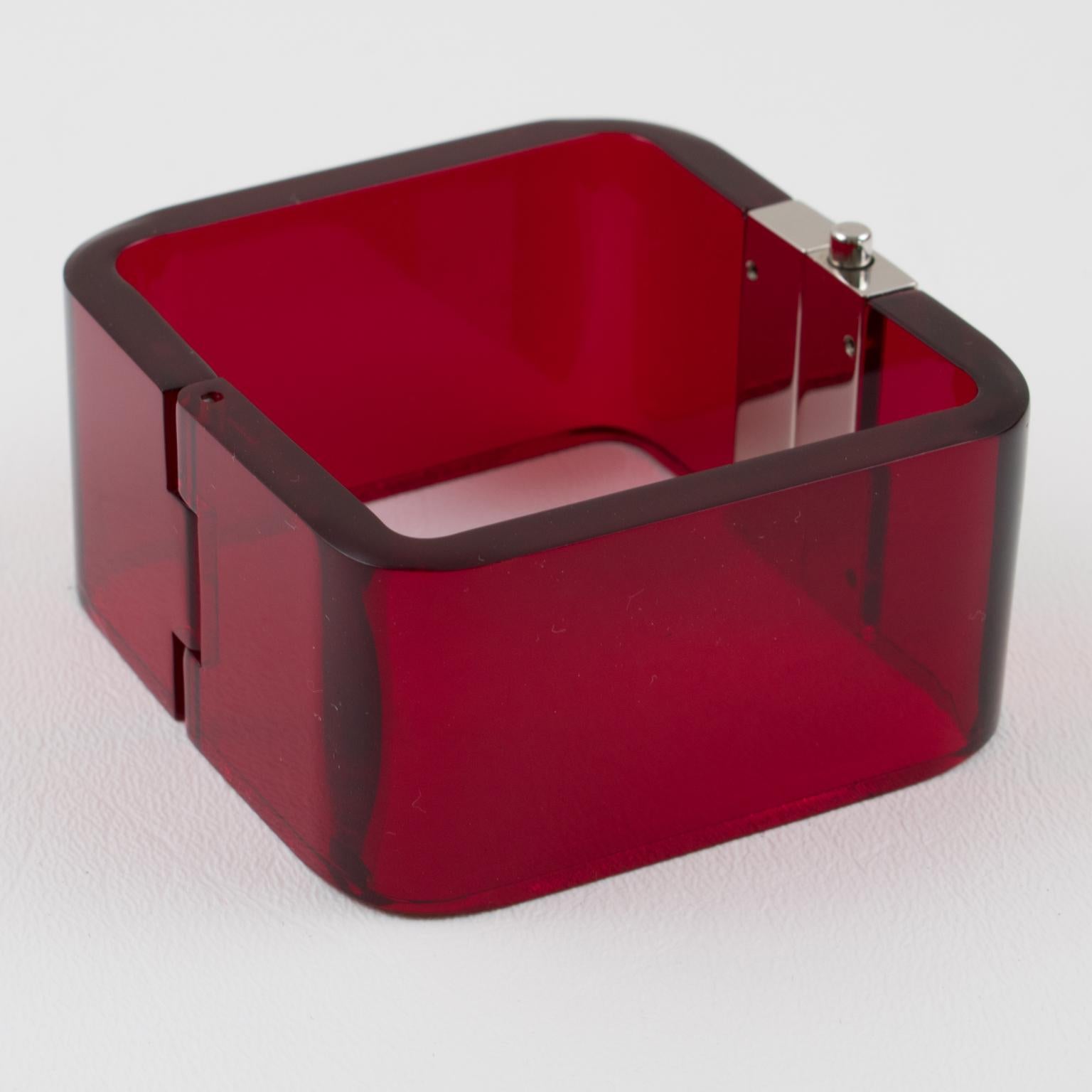 This gorgeous original Bottega Veneta Italy signed clamper bangle bracelet boasts a chunky square shape with transparent ruby red acrylic or Lucite complemented with large chromed metal clamper fastening. The piece is engraved on the outside of the