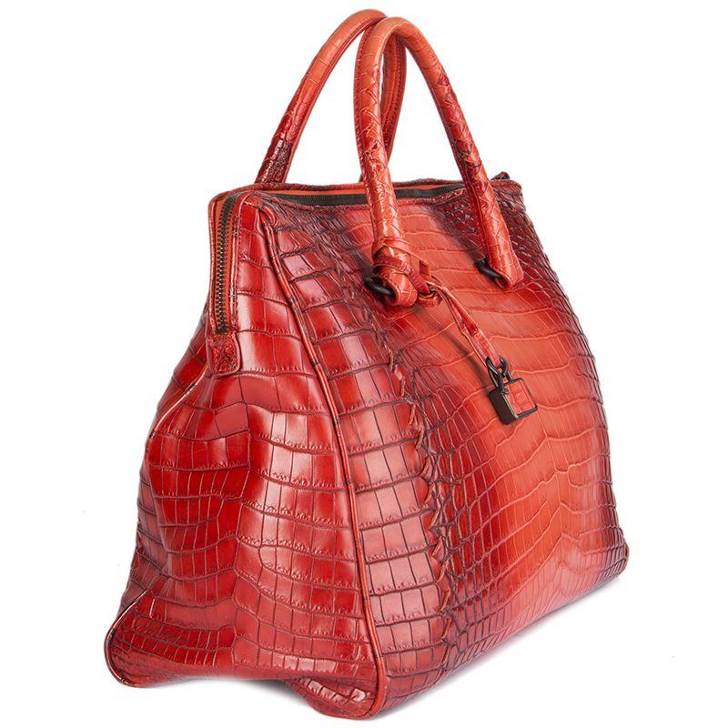 Bottega Veneta 'Cocco Glace Flannel' bag in patinated red crocodile leather. Closes with a two-way zipper on top. Lined in taupe suede with a zipper pocket against the back. Has been carried and is in excellent condition. Comes with key, lock,