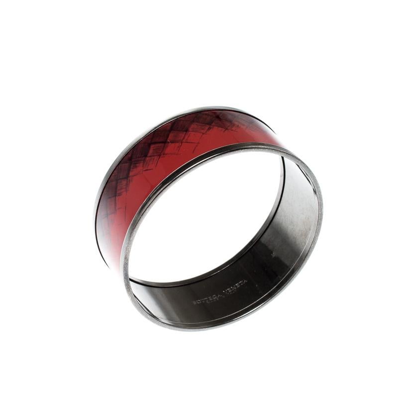 The house of Bottega Veneta brings to you a classy piece of jewellery to enhance your style. Crafted elegantly from gunmetal toned metal, this bracelet has red enamel coating all over with touches of the signature intrecciato pattern. This creation