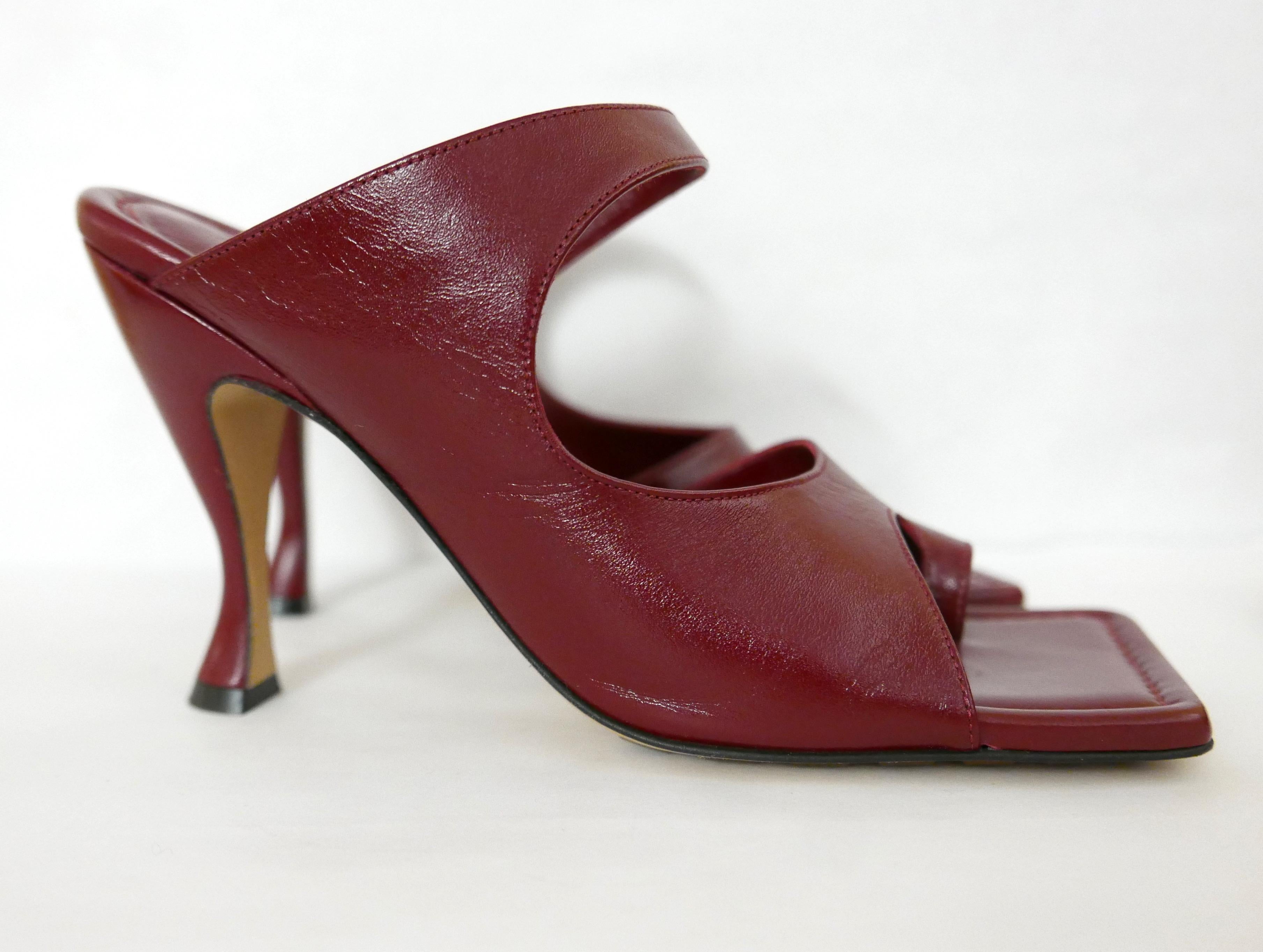 Super chic and sexy Bottega Veneta red leather mules from Resort 2020. 

Unworn with box, dustbags, spare heel tips and leaflet. 

Made from glossy ox blood red patent leather, they have a cool asymmetric cutaway shape, signature square toe with