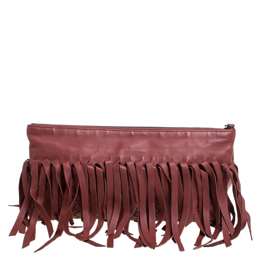 This statement clutch from Bottega Veneta will never fail to grab you compliments. It has been crafted from brown leather and styled with signature Intrecciato pattern and fringe details. It has a top zip closure that opens to a fabric-lined