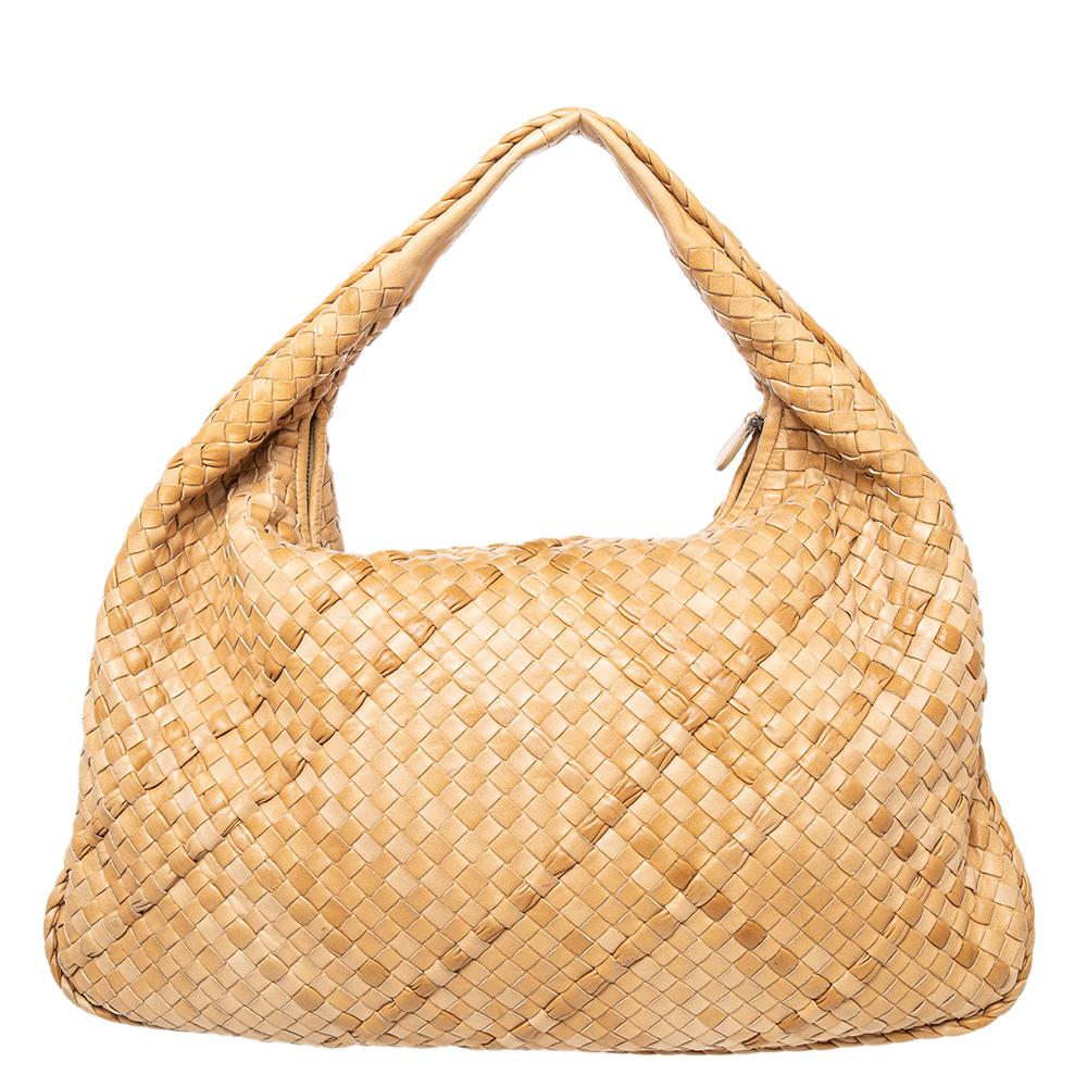 The excellent craftsmanship of this Bottega Veneta hobo ensures a brilliant finish and a rich appeal. Woven from leather in their signature Intrecciato pattern, the beige-hued bag is provided with a loop handle and a top zip closure, which secures a