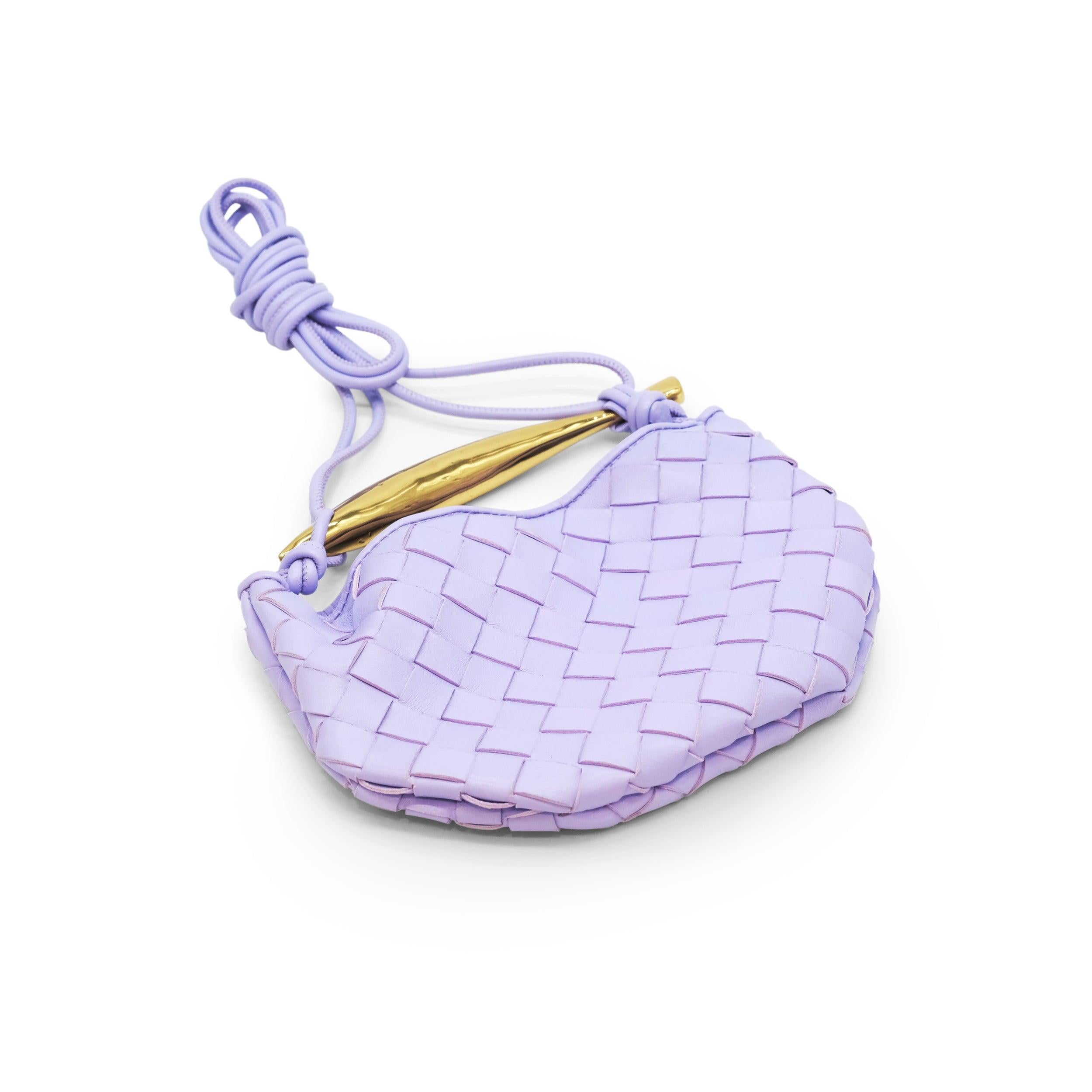 The Bottega Veneta Mini Sardine Bag in Amethyst is a stunning piece that exemplifies the brand's commitment to craftsmanship and innovative design. Made from intrecciato-woven lambskin leather, this bag boasts a unique, slouchy silhouette that is