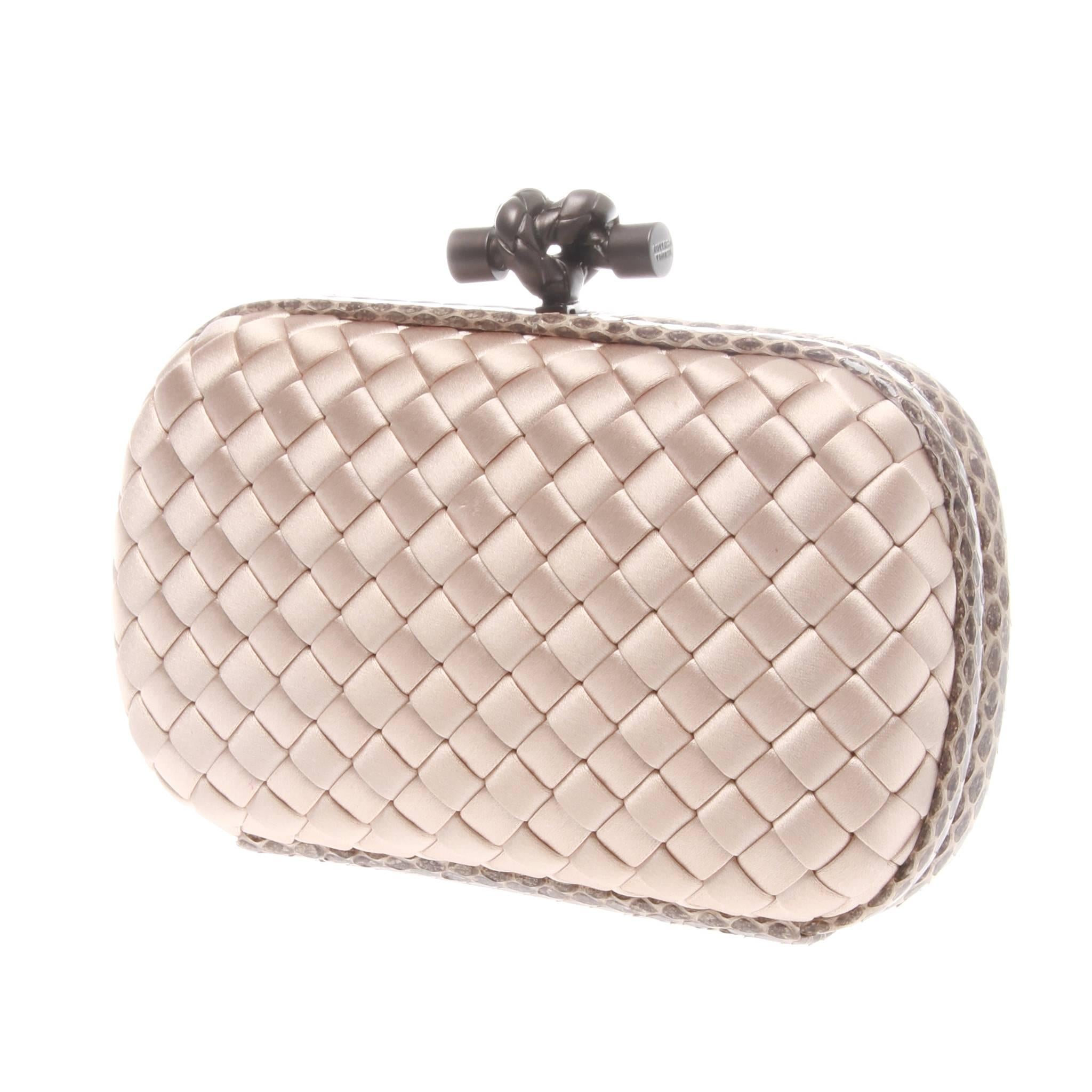 A exceptional beige clutch crafted in BOTTEGA VENETA Watersnake-trimmed Intrecciato Satin style that will hold its own against any glamorous evening look.
Blush pink intrecciato woven satin body.
Taupe matte hardware.
Hard-shell body closes with