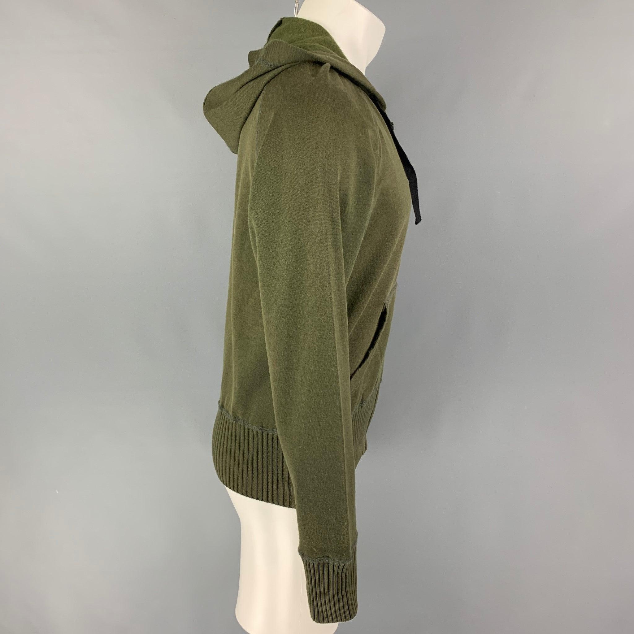BOTTEGA VENETA sweatshirt comes in a olive cotton featuring a hooded style, ribbed hem, front pockets, black woven leather trim, and a full zip up closure. Made in Italy.
Very Good
Pre-Owned Condition. Small mark at front.  

Marked:   50