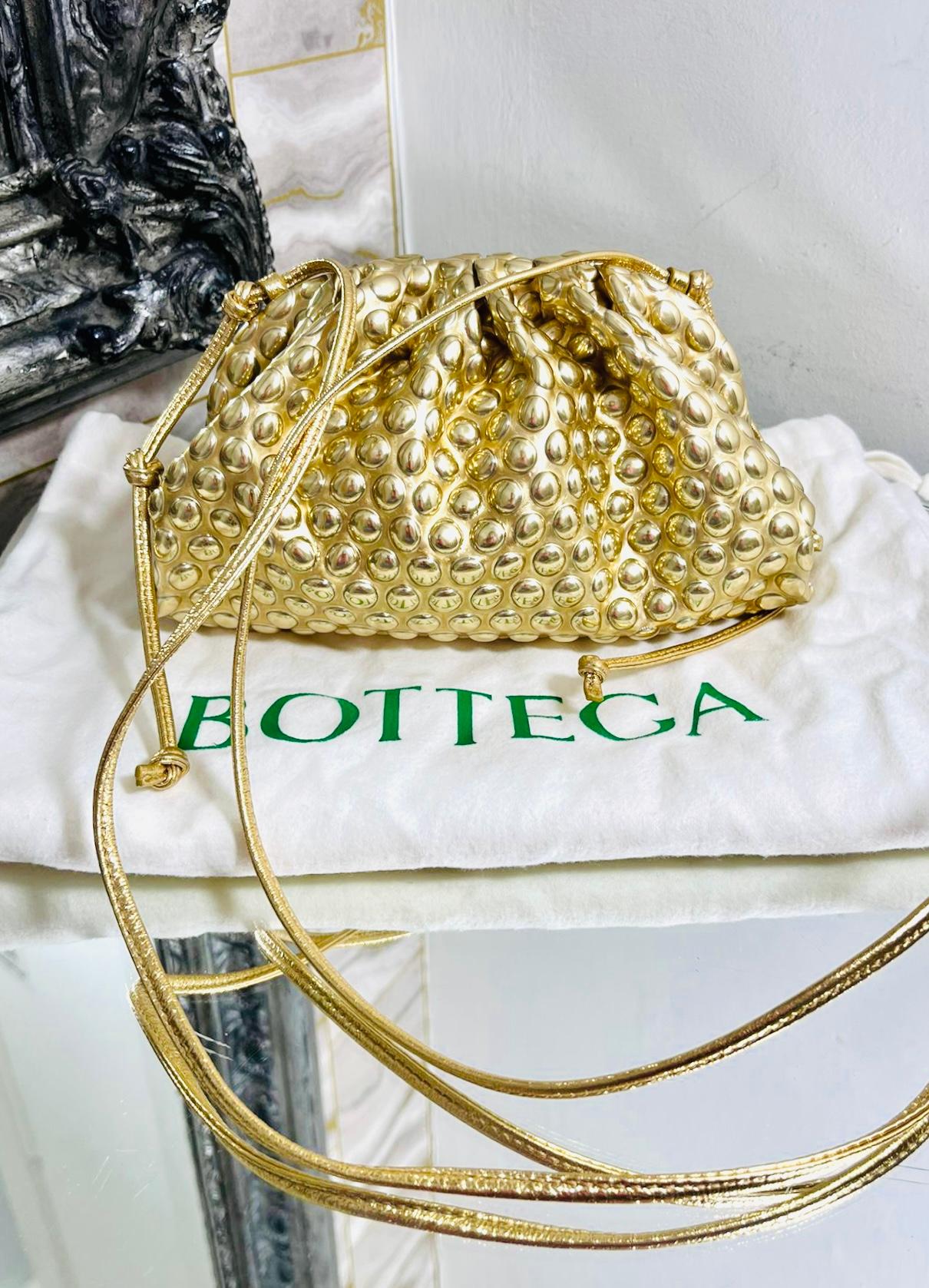 Bottega Veneta The Mini Pouch Crossbody Bag

Gold bag embossed with metallic dots pattern throughout.

Detailed with ruched magnetic frame top leading to silver interior.

Featuring long, thin leather crossbody strap accented with the brand's