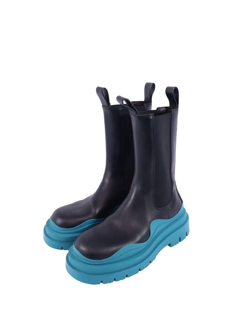 A bold reinterpretation of the Chelsea boot, these Bottega Veneta black leather lug boots are the ultimate in modern luxury footwear. Designed with a sleek black upper and contrasting signature turquoise blue rubber sole, they deliver an instant