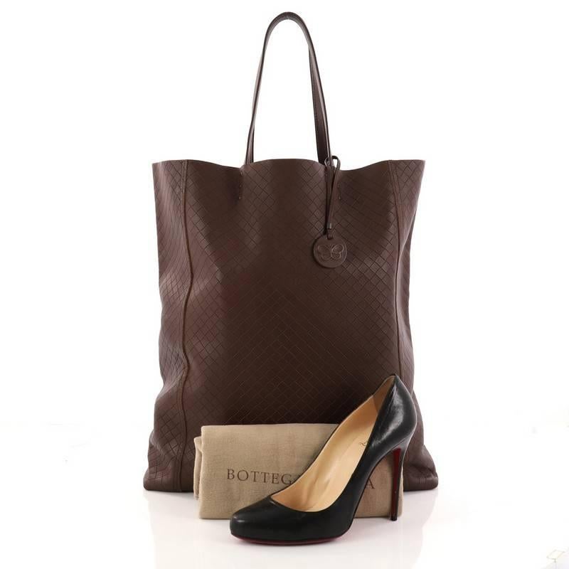 This authentic Bottega Veneta Tote Intrecciomirage Leather Tall is a chic bag perfect for your everyday use. Crafted from brown intrecciomirage leather, this bag features dual tall leather top handles and gunmetal-tone hardware accents. Its wide